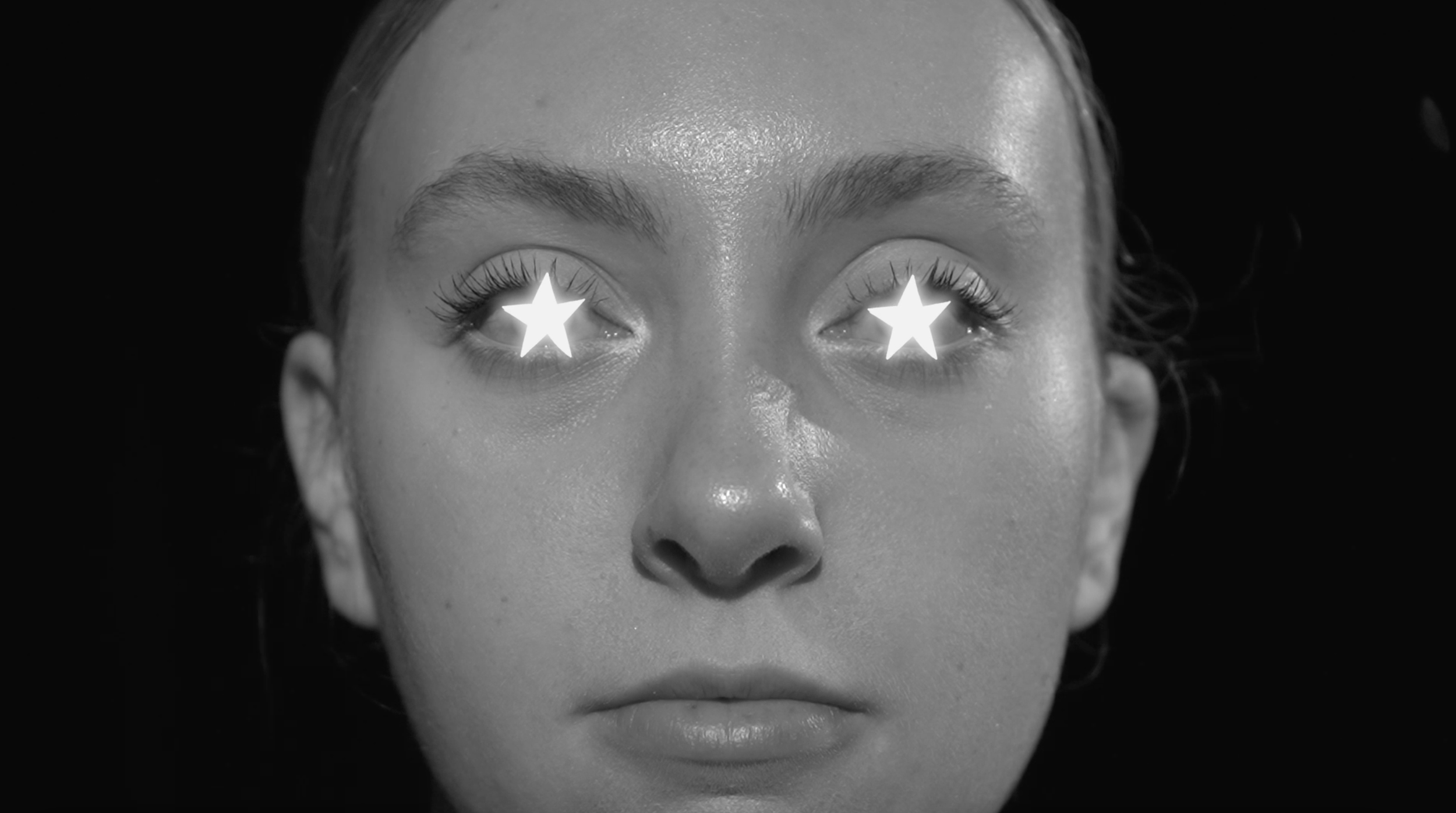 A close-up black and white photo of a woman's face with star-shaped filters over her eyes.
