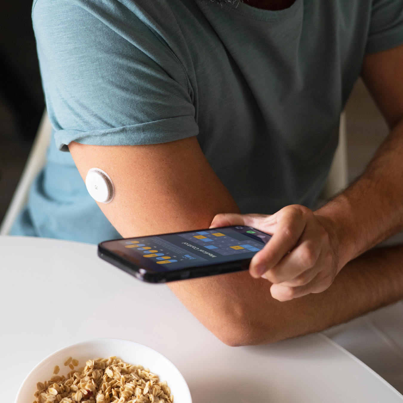 Diabetic man checking his glucose patch sensor on his smartphone.