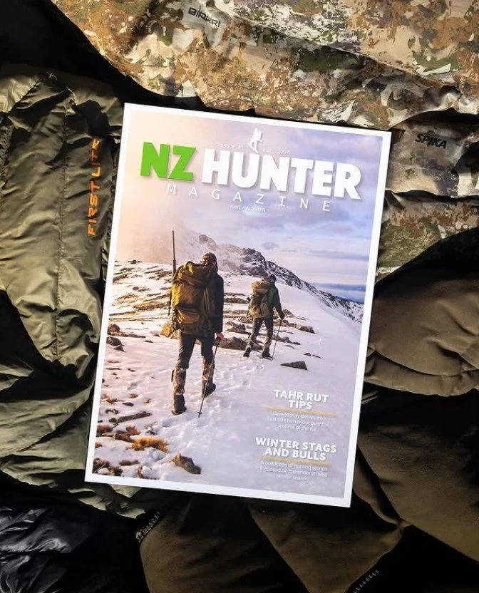 Cover of NZ Hunter magazine showing two people hiking in snowy mountain terrain, dressed in outdoor gear.