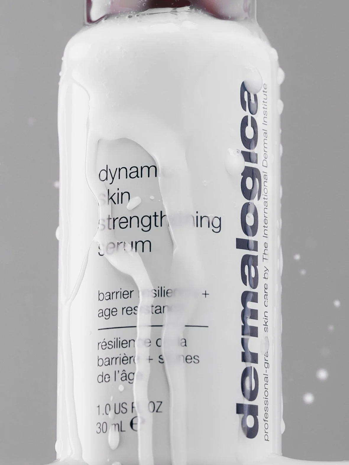A white bottle of Dermalogica skin care product with water splashed on it.