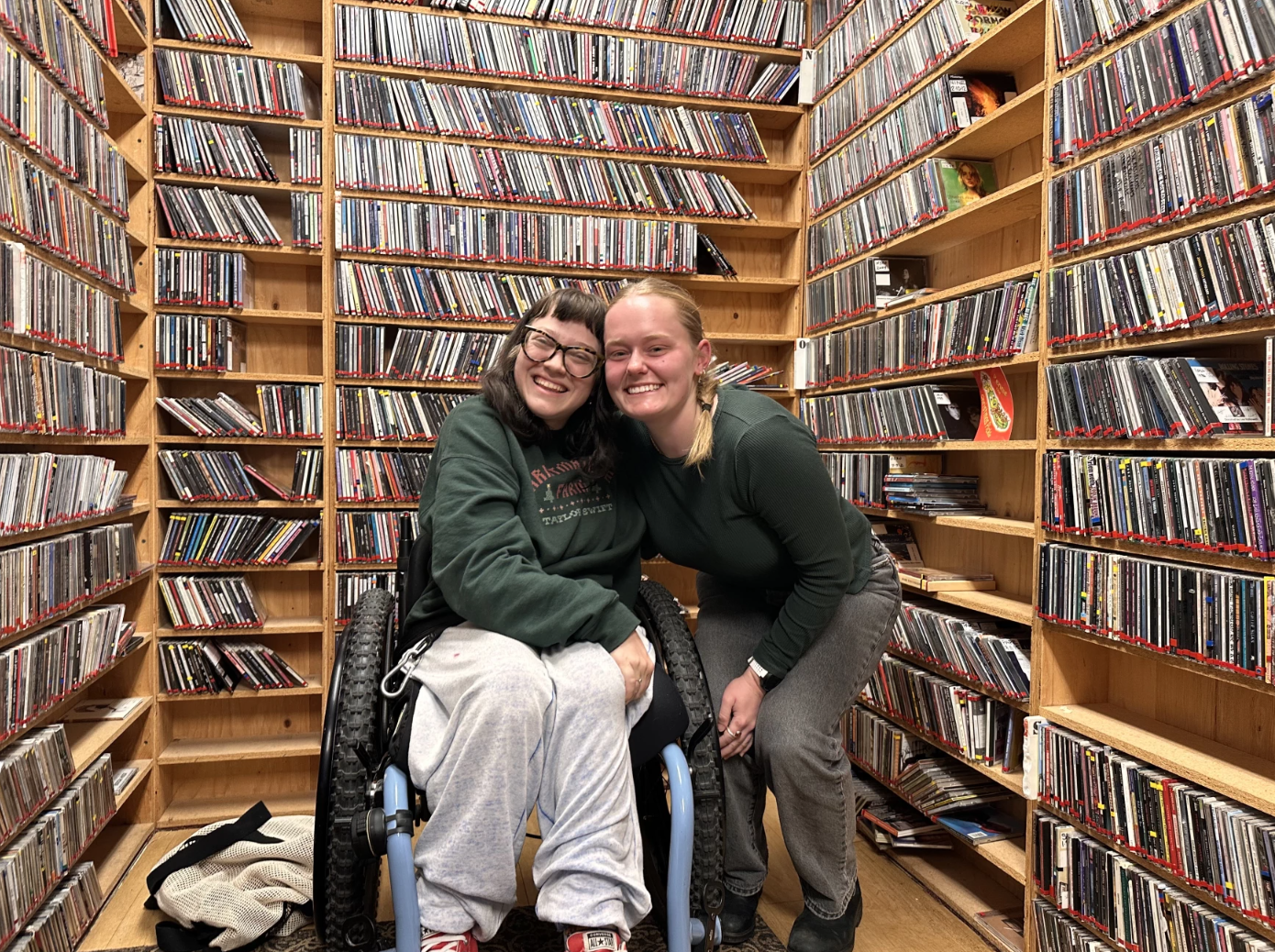 Two individuals smile for a portrait in front of a book shelf.