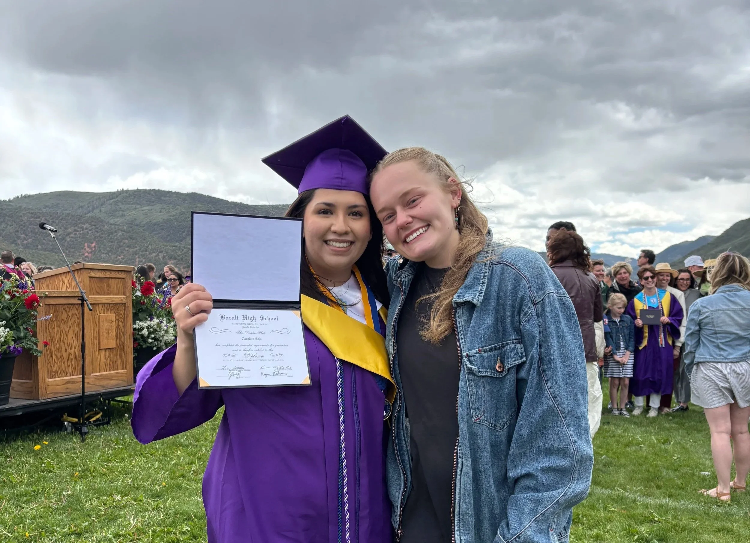 Megan Mindy, Commonground founder, right, smiles besides a female high school graduate wearing a cap and gown.