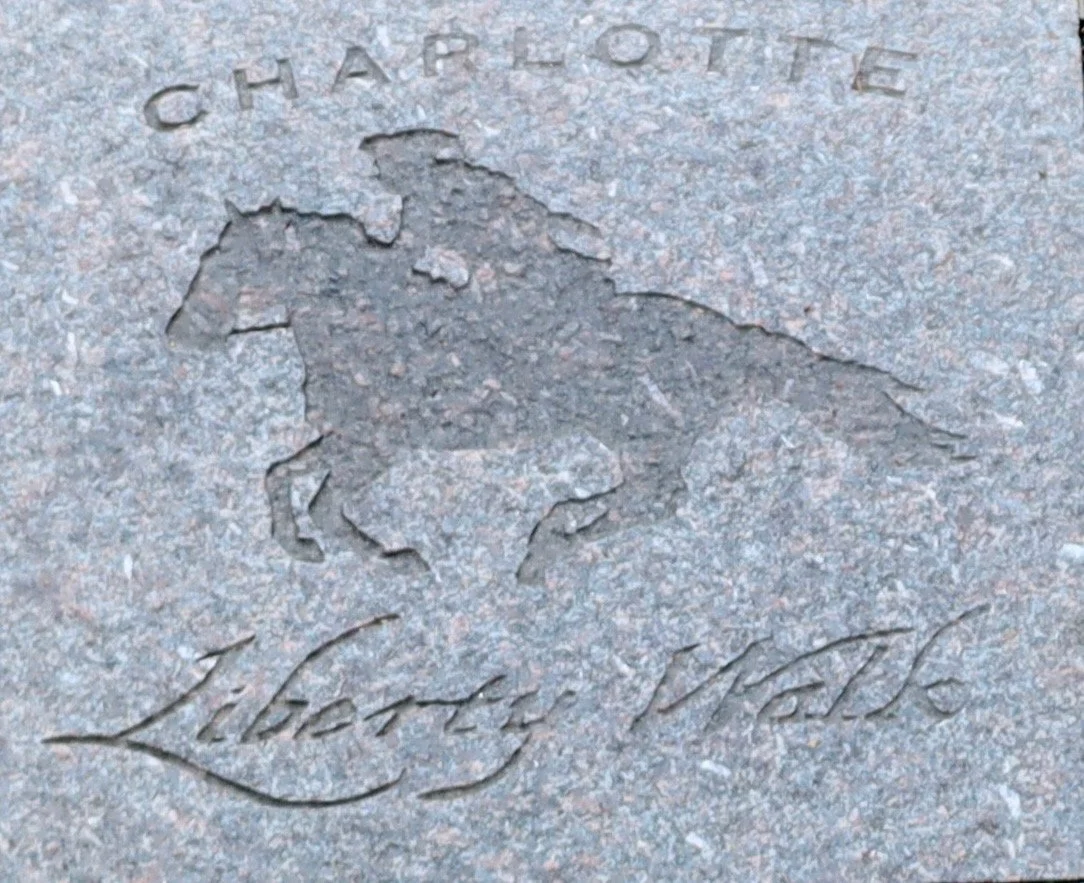 Engraved image of a horse with the words 'Charlotte' above and 'Liberty Walk' below on a stone surface.