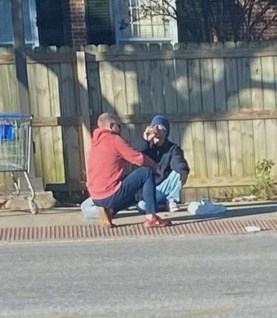 Two people kneeling on the sidewalk praying.