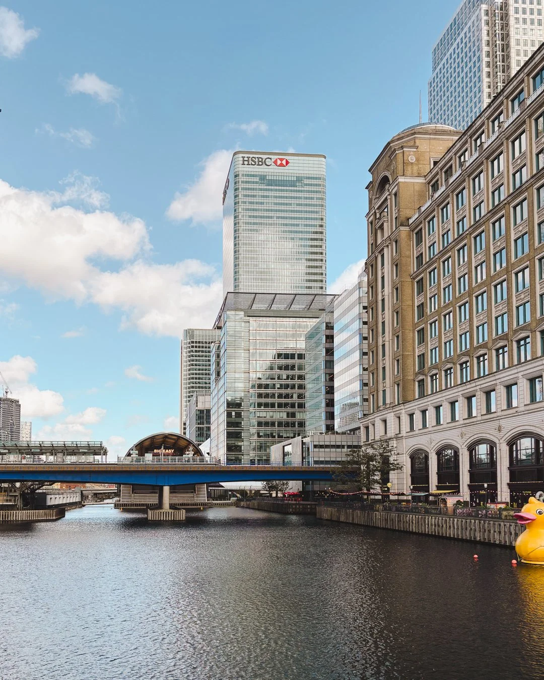 View of Canary Wharf and riverside buildings in London on a bright day.