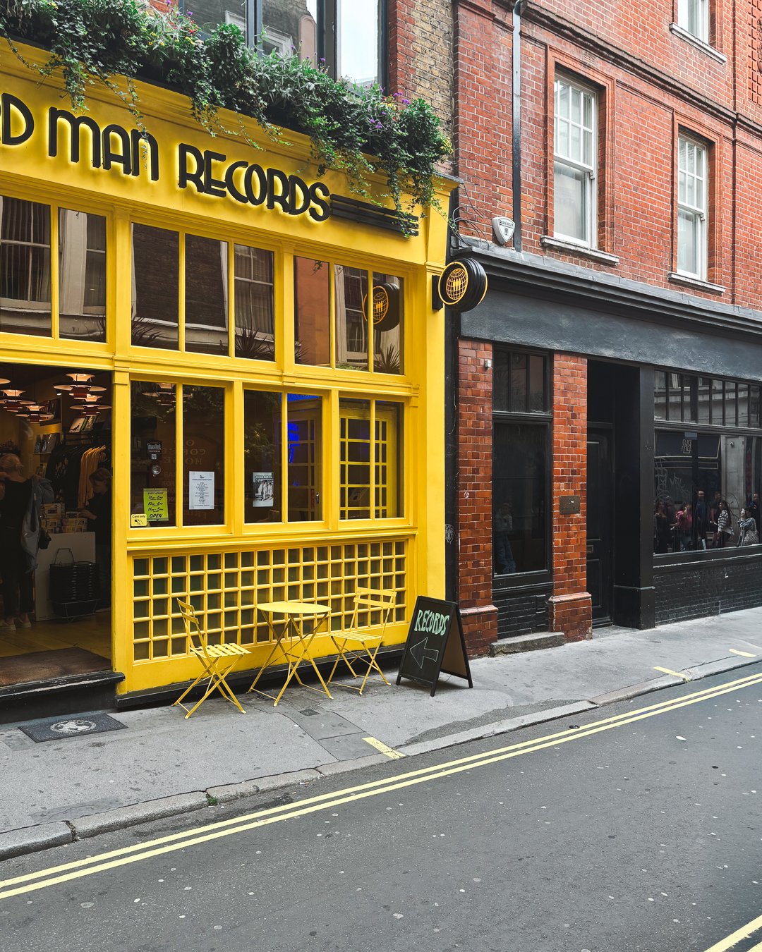 Yellow record shop storefront on a London street with brick buildings beside it.
