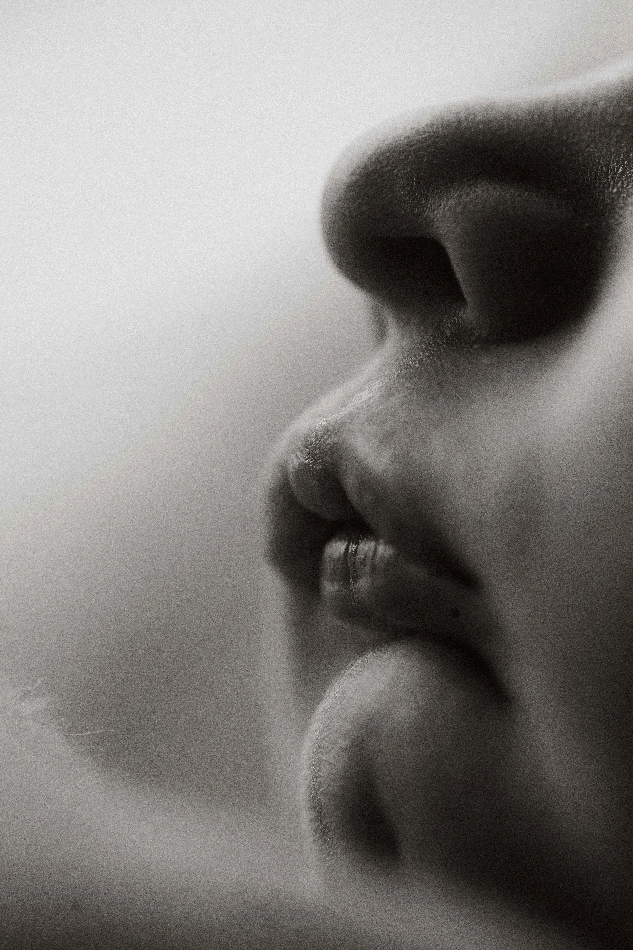 Close-up of a person's nose and lips in black and white.