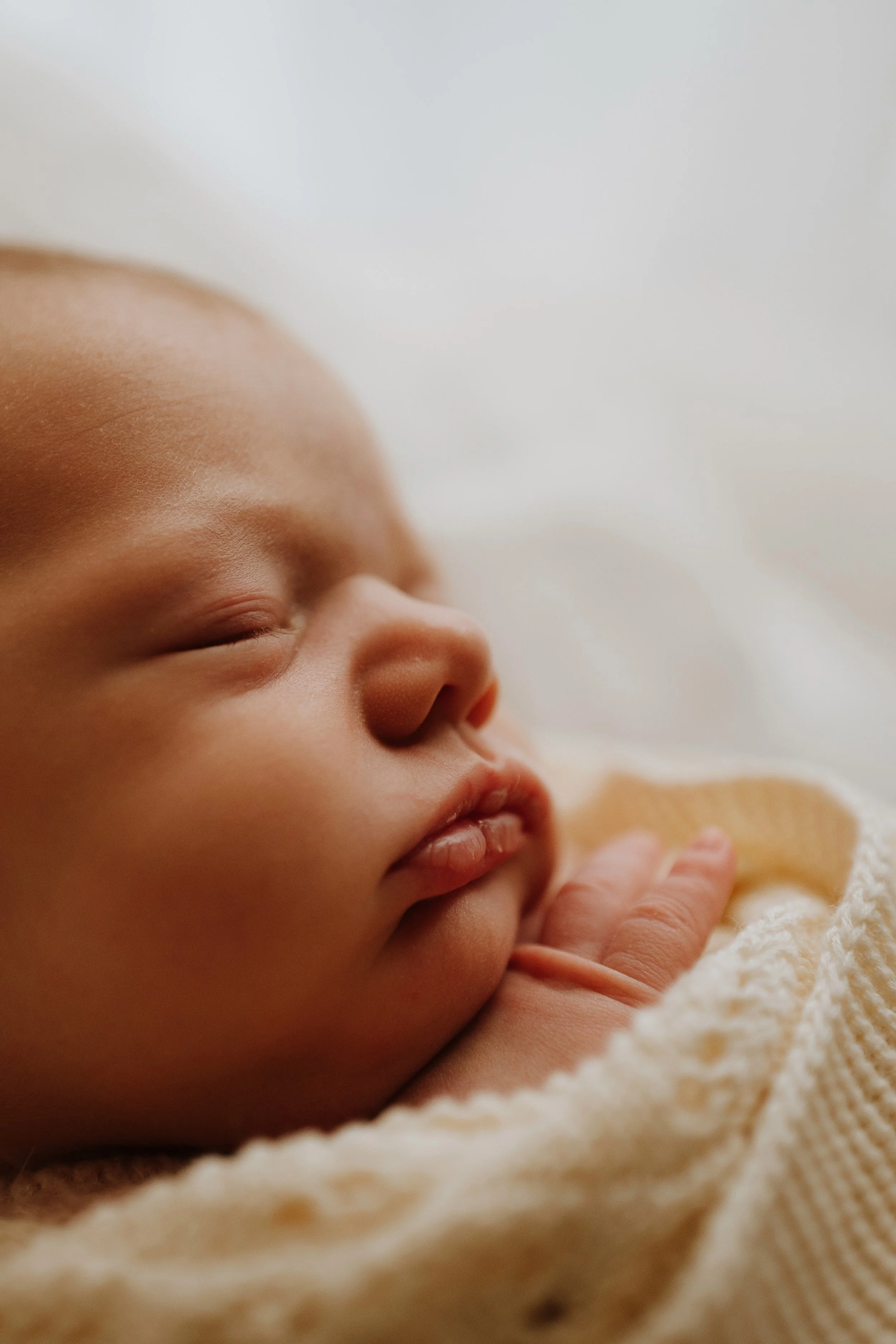 Close-up of a sleeping baby's face peacefully resting on a soft blanket.