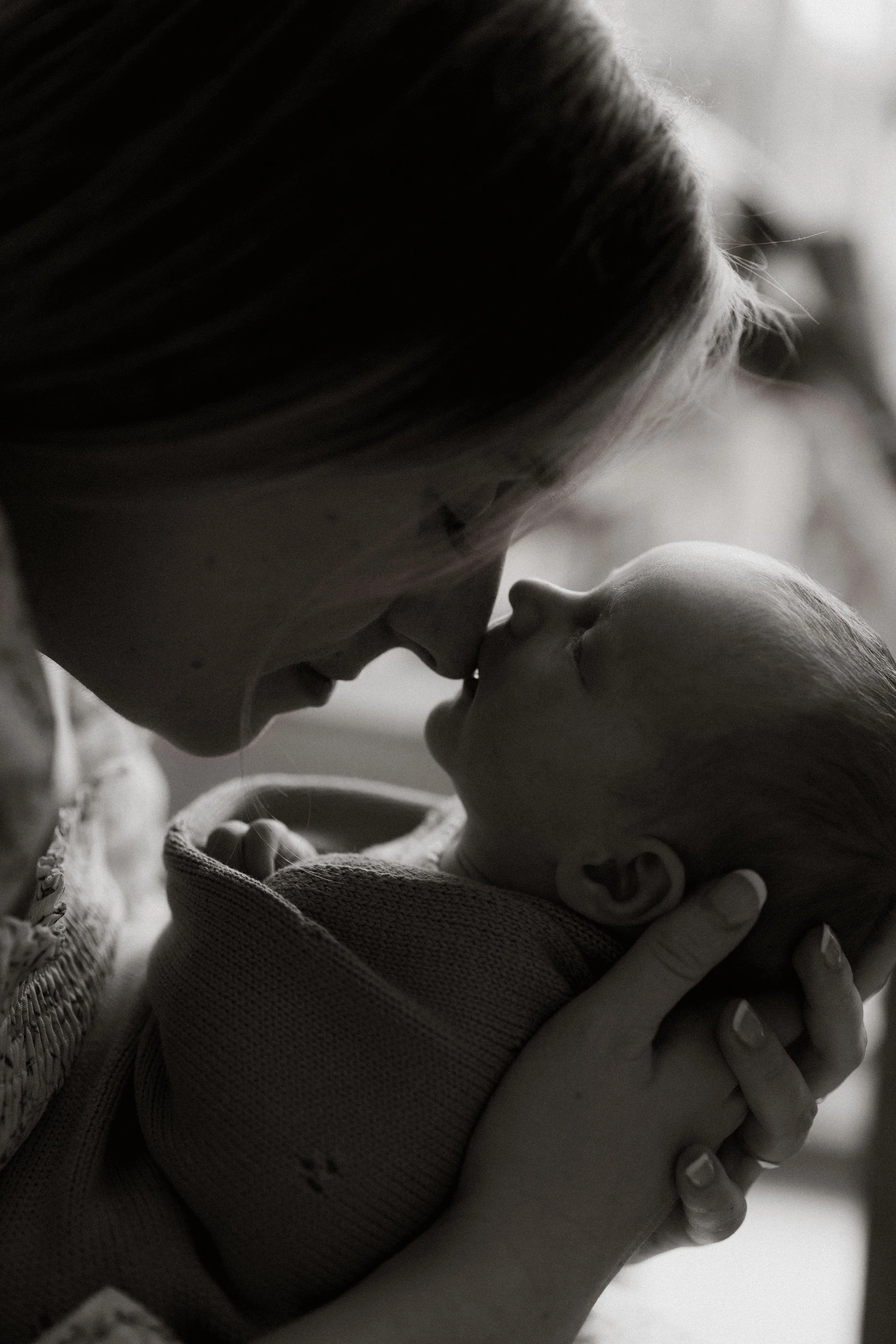 A woman holding a baby close, with their noses touching, in a tender moment.