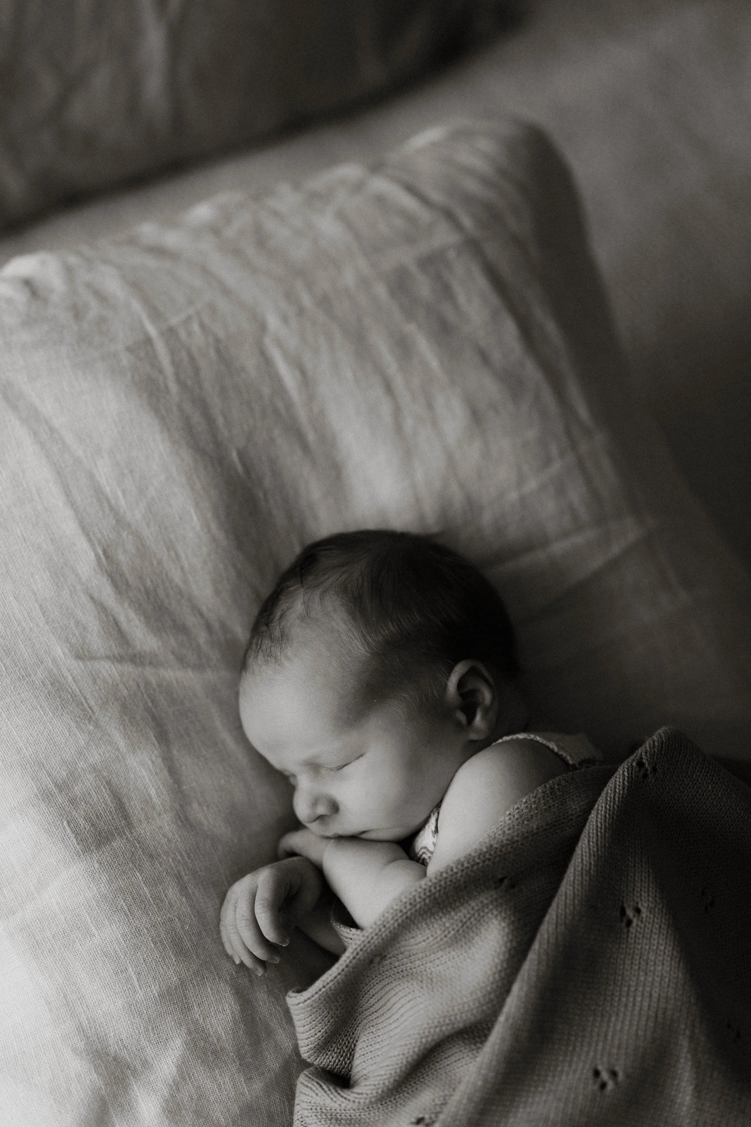 A young child with short hair and closed eyes, peacefully sleeping on a soft surface, wearing casual clothing.