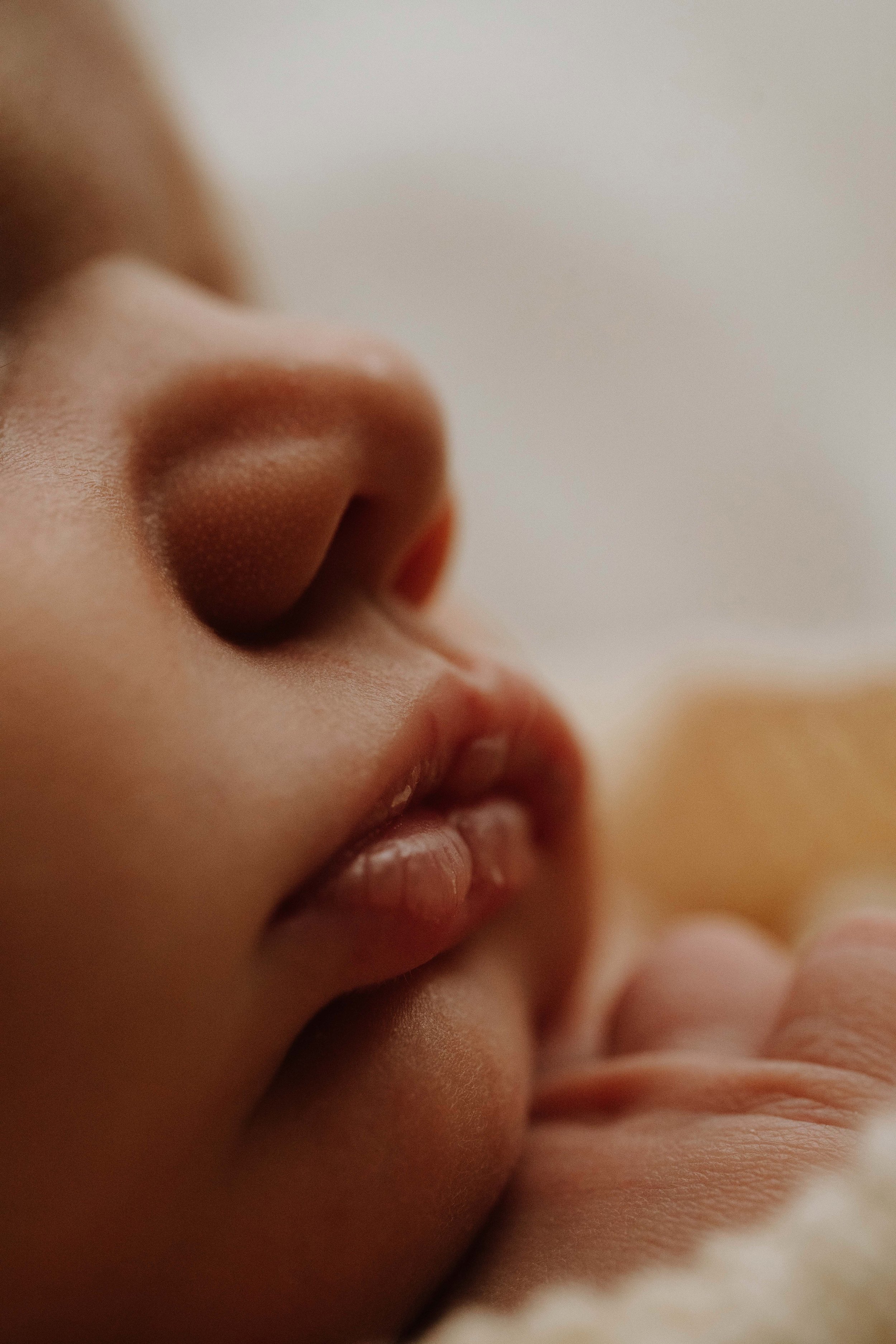 Close-up view of a person's nose, lips, and part of their face with soft lighting.
