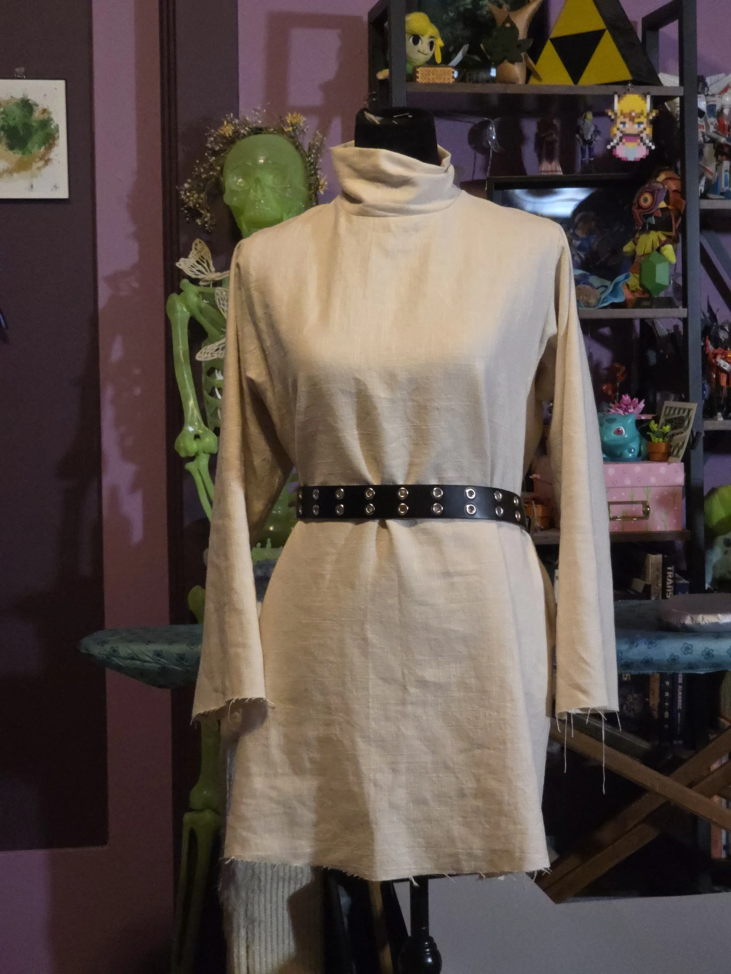 off-white linen tunic with a brown leather belt on a dress form. It had long sleeves and a turtleneck