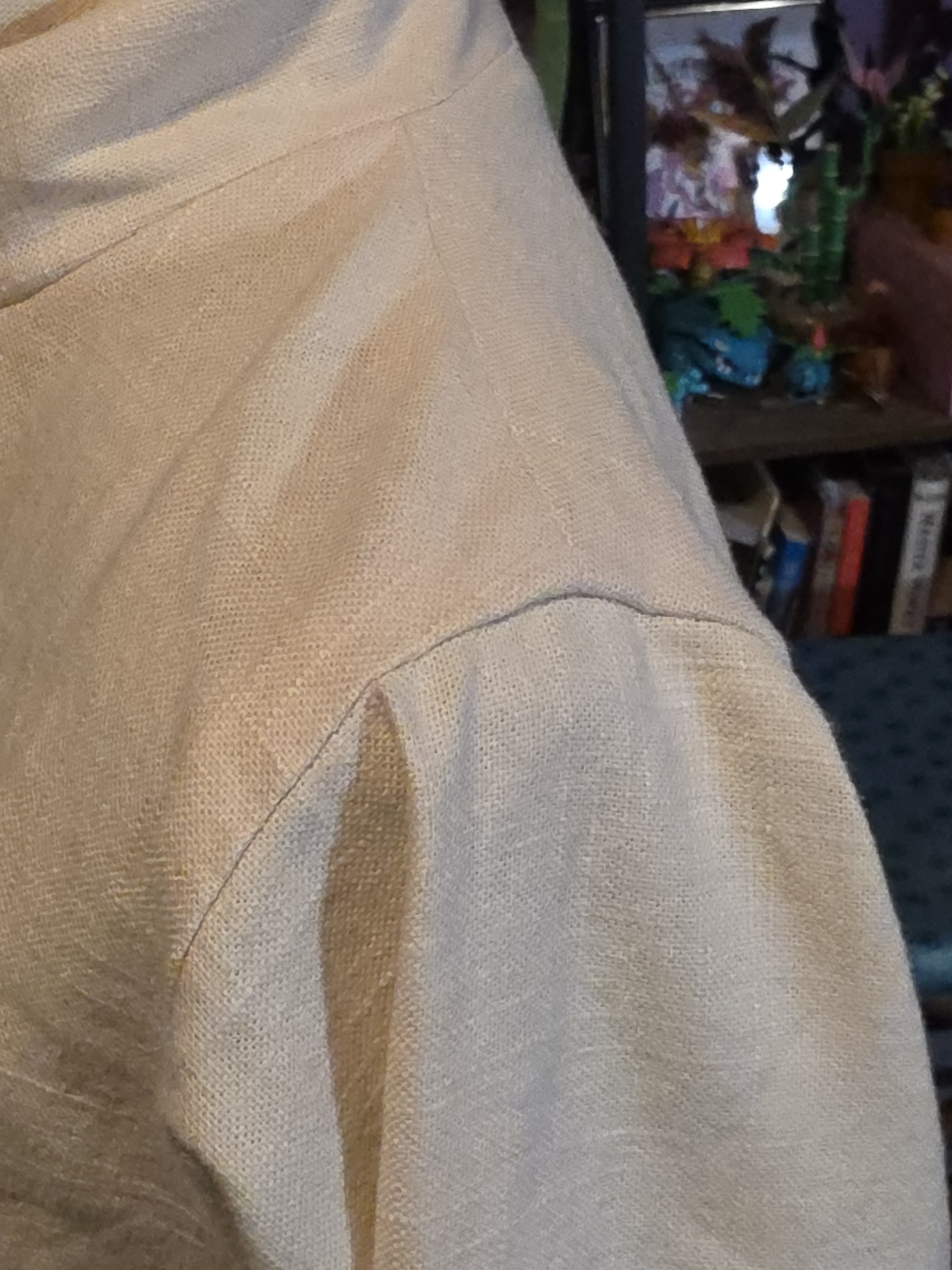 closeup of the shoulder of an offwhite linen tunic, showing clean, pressed seams