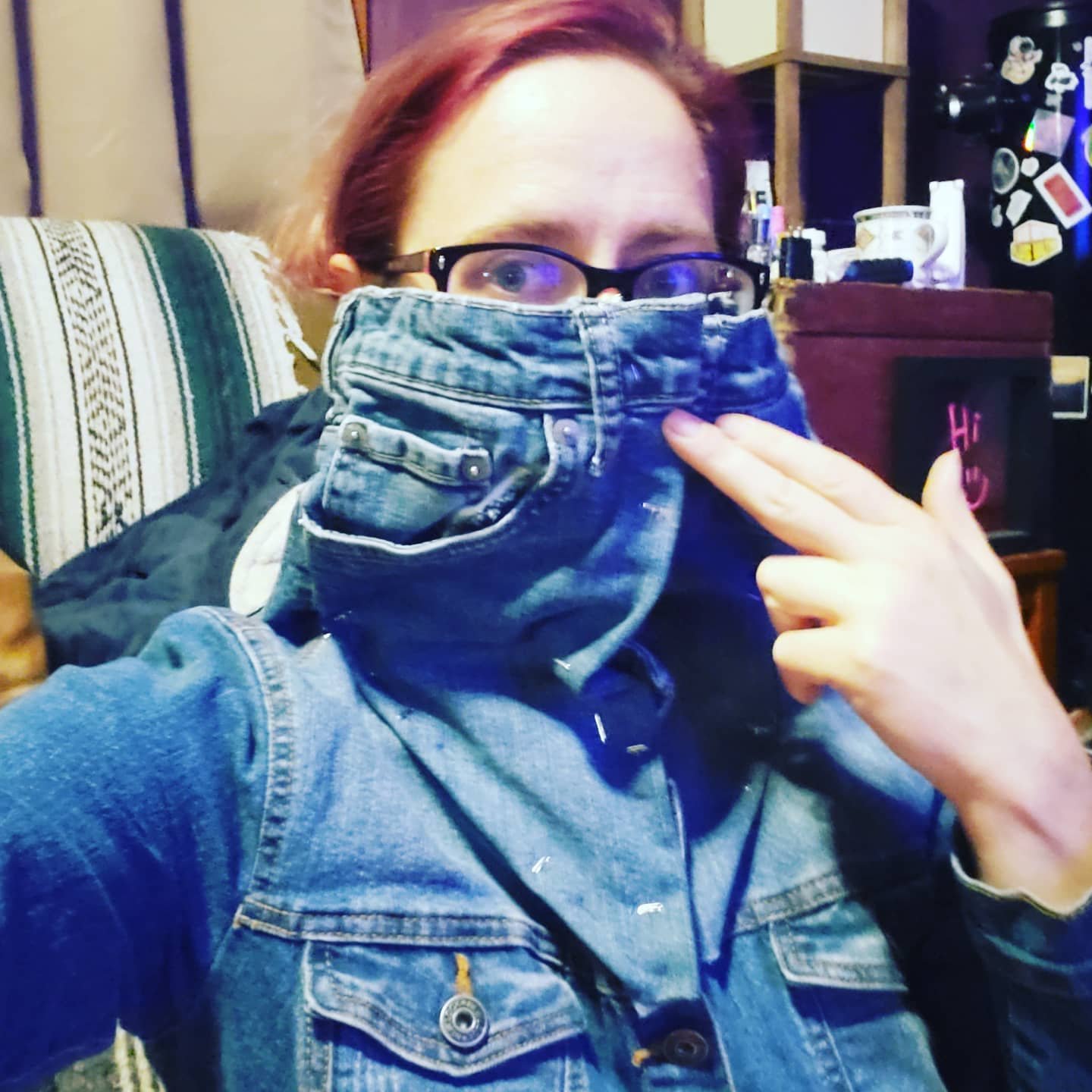 woman wearing a basted together denim sewing project where the top of some childrens jeans are turned into a high collar for a denim shirt that is worn under a denim vest