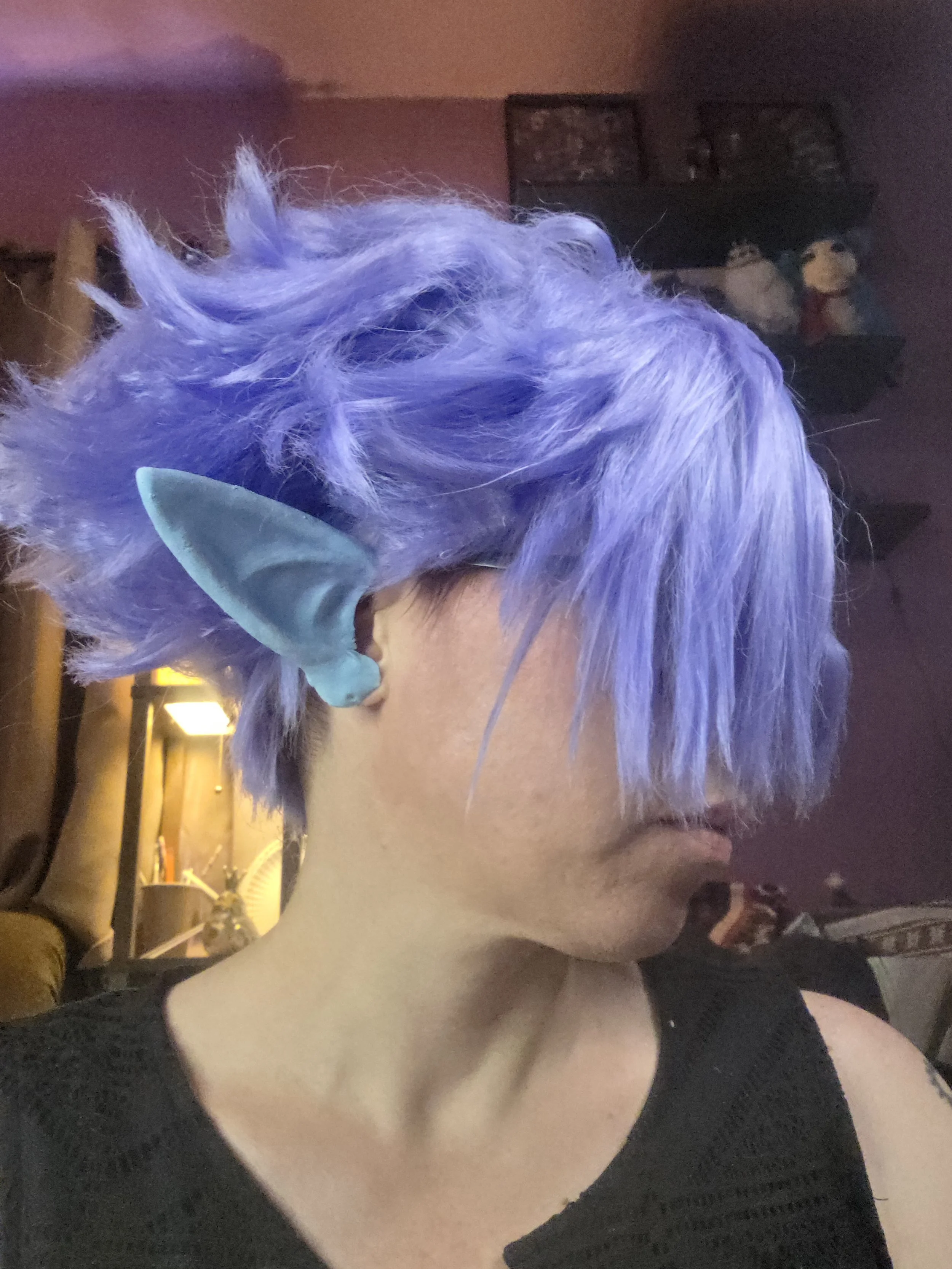 cosplayer wearing a lavender wig and pale blue pointy ears. The wig has long bangs combed over one eye