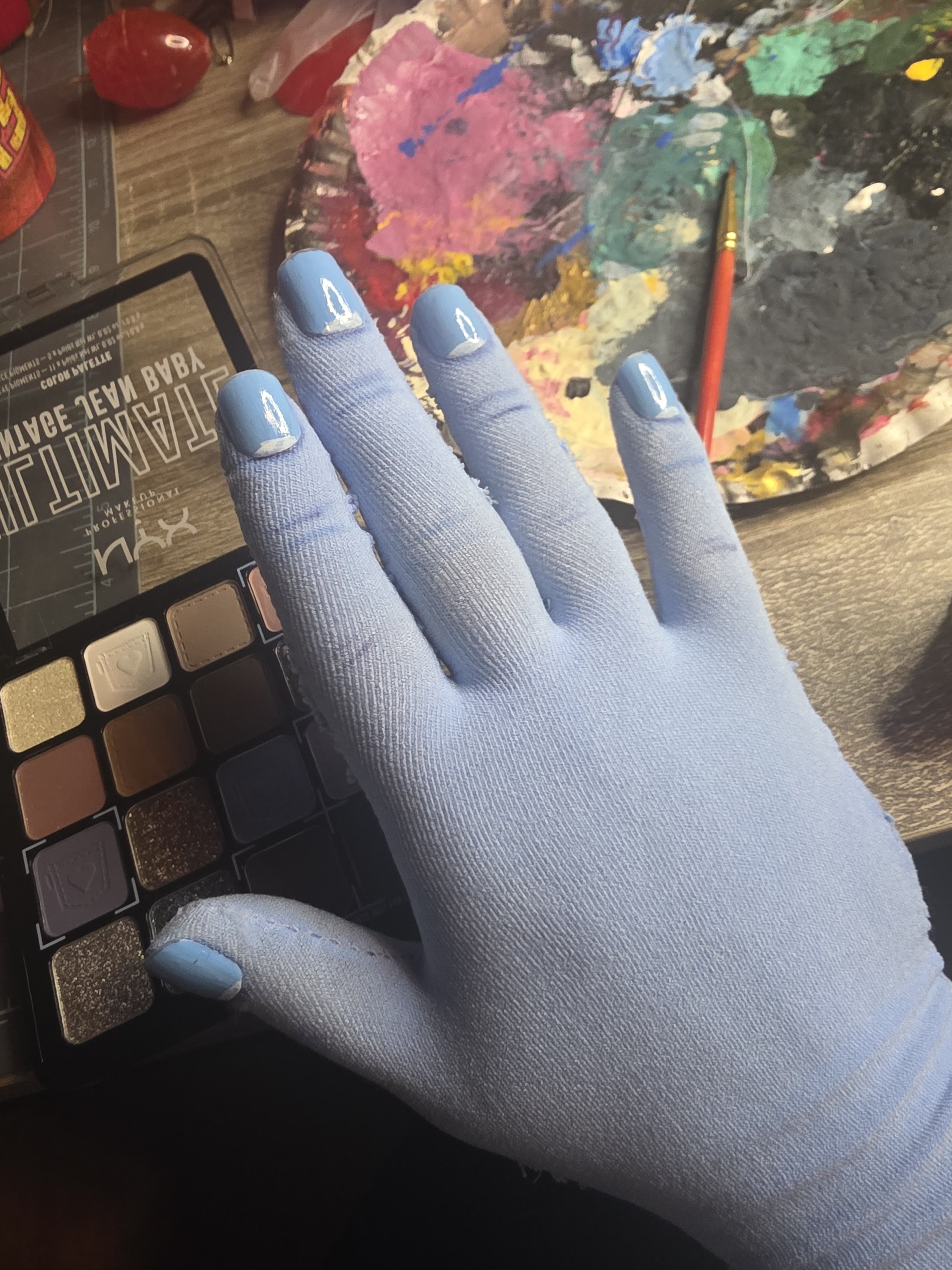 hand in a glove made of pale blue tights. It has a smooth, snug fit, and detailed painting on the nails