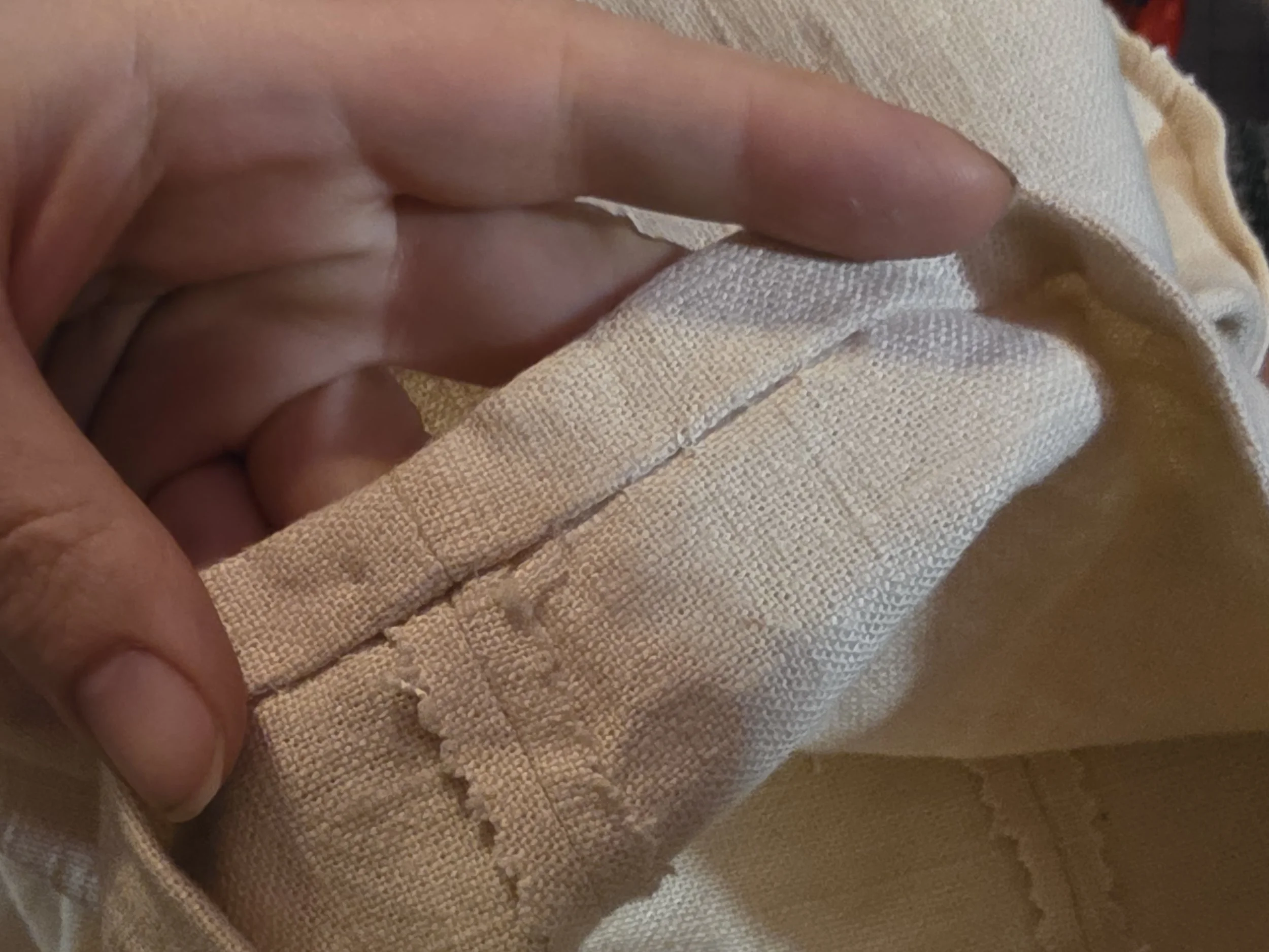 blind hem on the cuff of off-white linen pants. the inside seam has been pinked (cut in a zigzag edge), and the inside hem is stitched only into single threads, so no stitching is visible on the outside