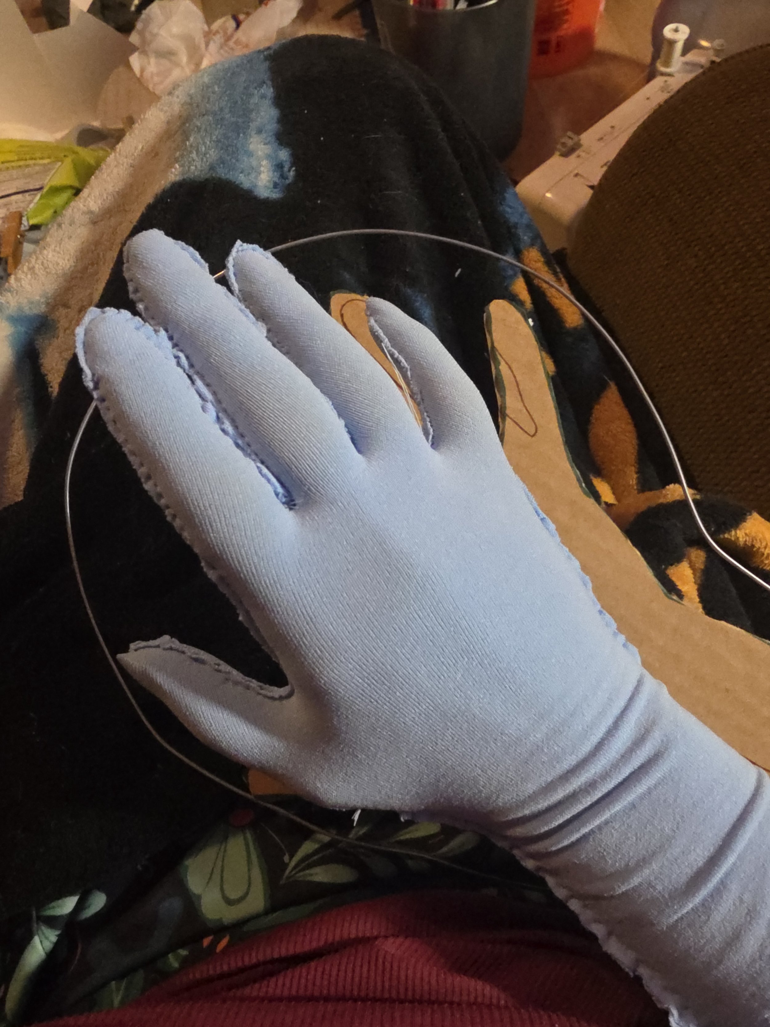 hand in a glove made of pale blue tights, with stitching visible around the sides