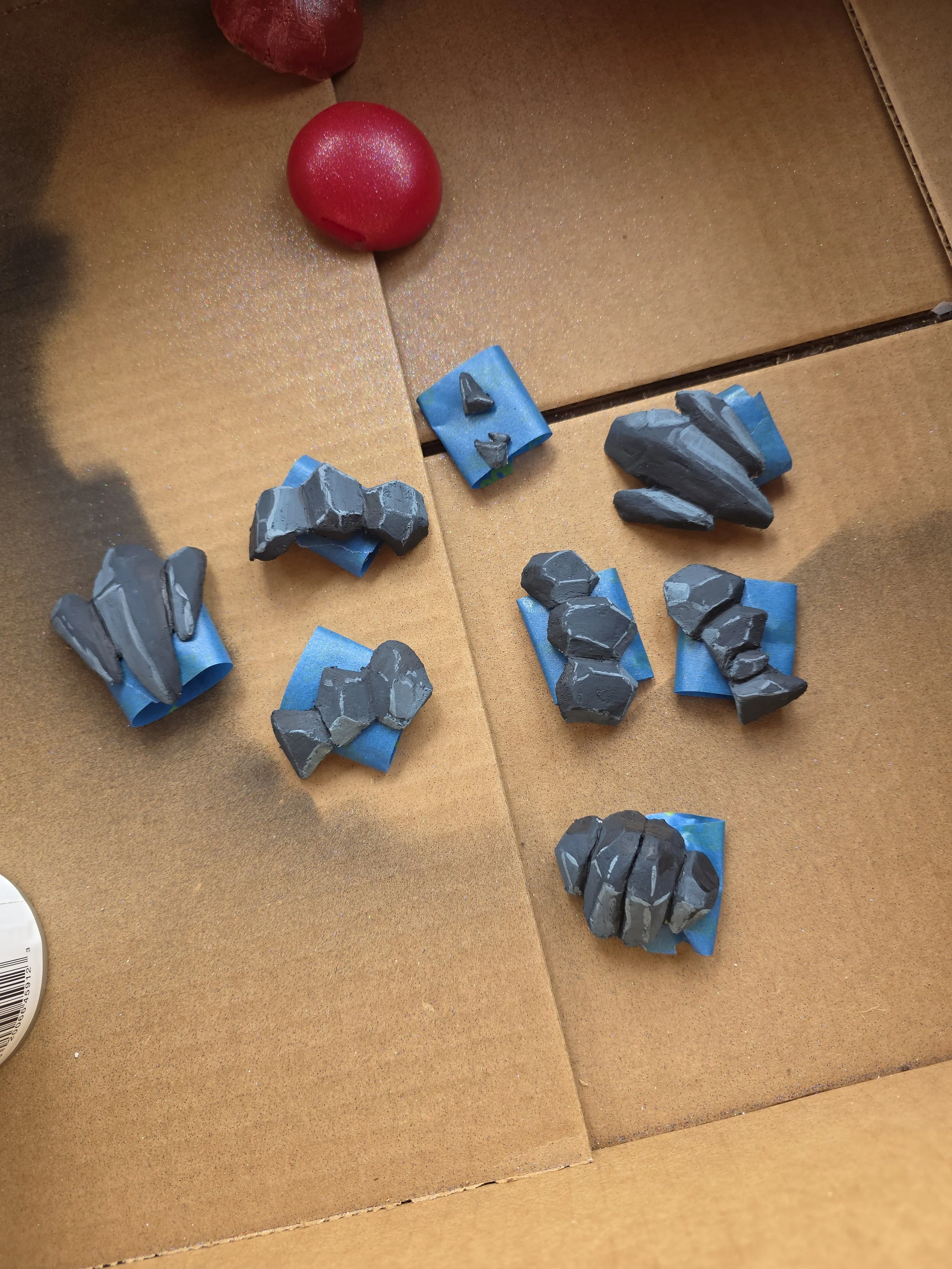 cardboard box with rock-like scales made of worbla. smooth, angular planes on each rock are painted different shades of blueish gray to create shading