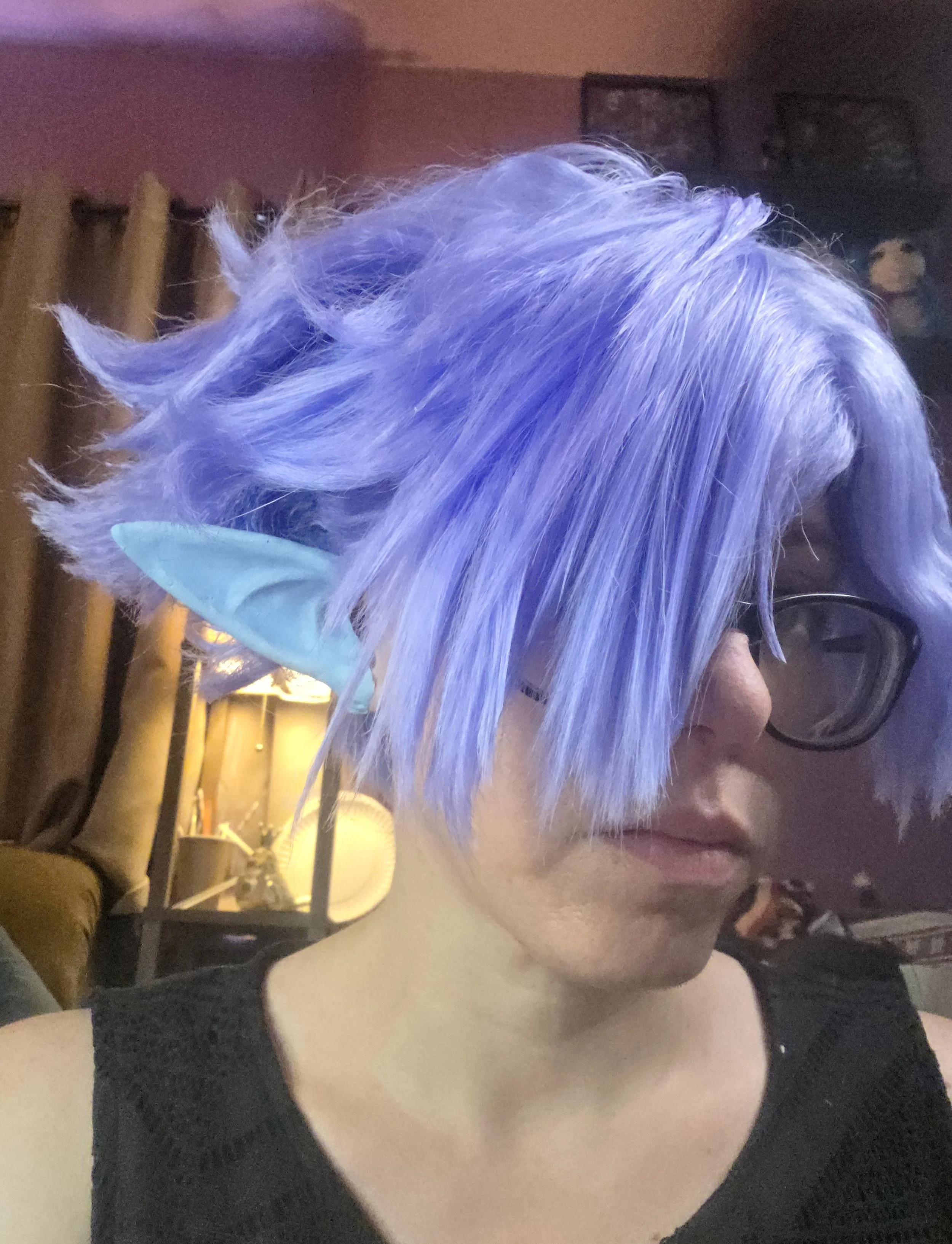 cosplayer wearing a lavender wig and pale blue pointy ears. The wig has long bangs combed over one eye