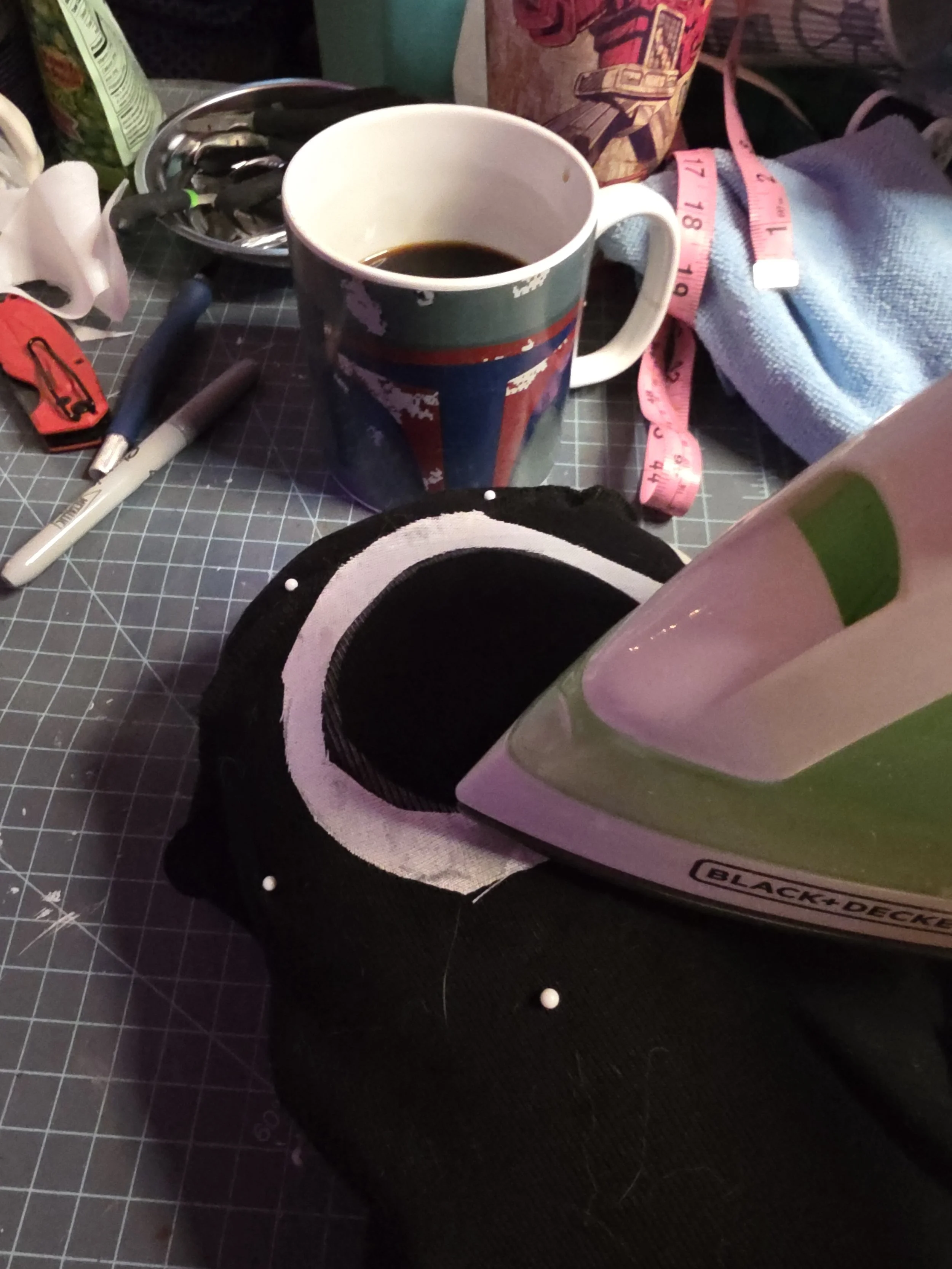 Point of an iron pressing interfacing fabric around the eye hole of an inside out ninja mask