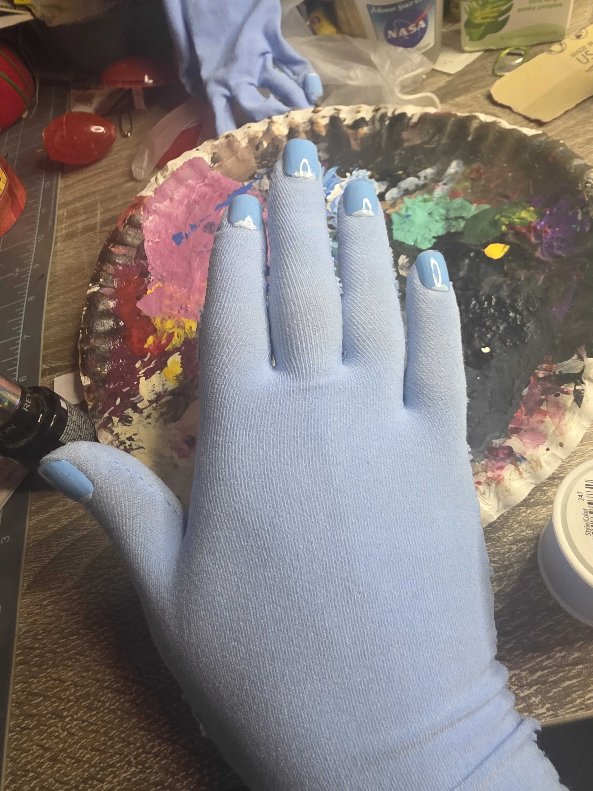 hand in a glove made of pale blue tights. It has a smooth, snug fit, and detailed painting on the nails