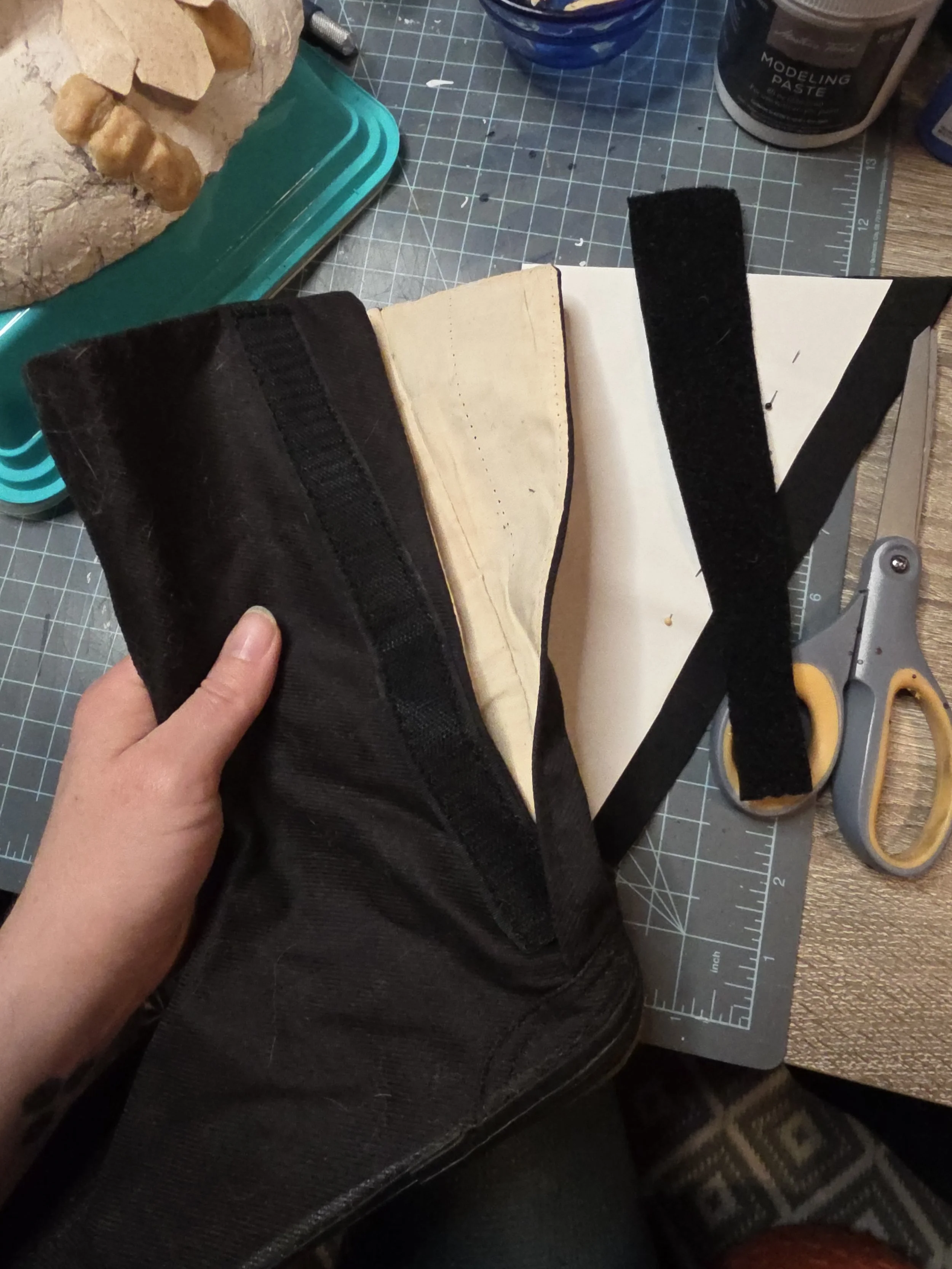 The inside of a black canvas boot, lined with unbleached fabric. A wide velcro strip has been removed from the opening