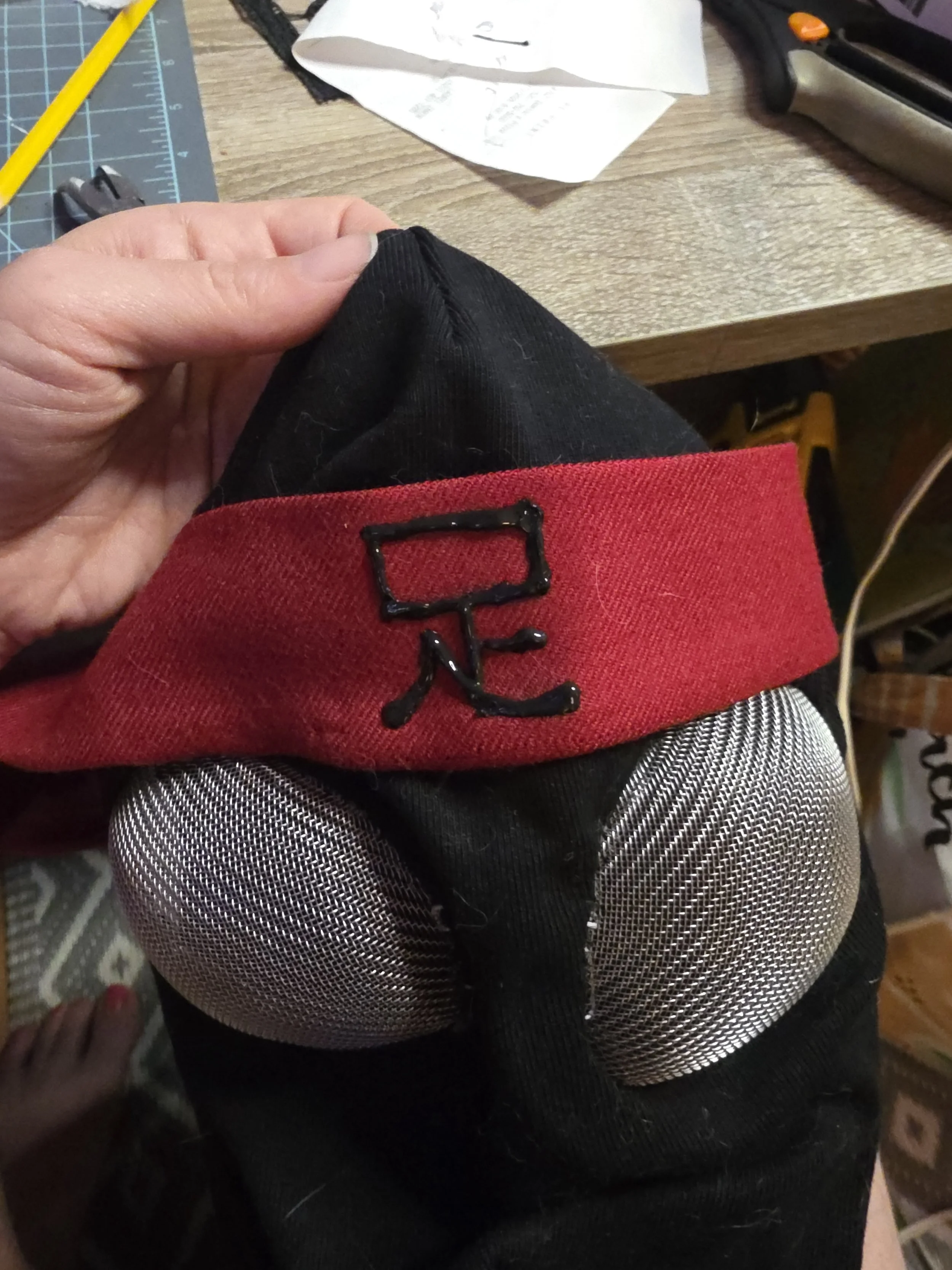 Black ninja hood with bug-like metal mesh eye covers and a red headband. The Japanese kanji for Foot is written on the center of the headband in black puffy fabric paint