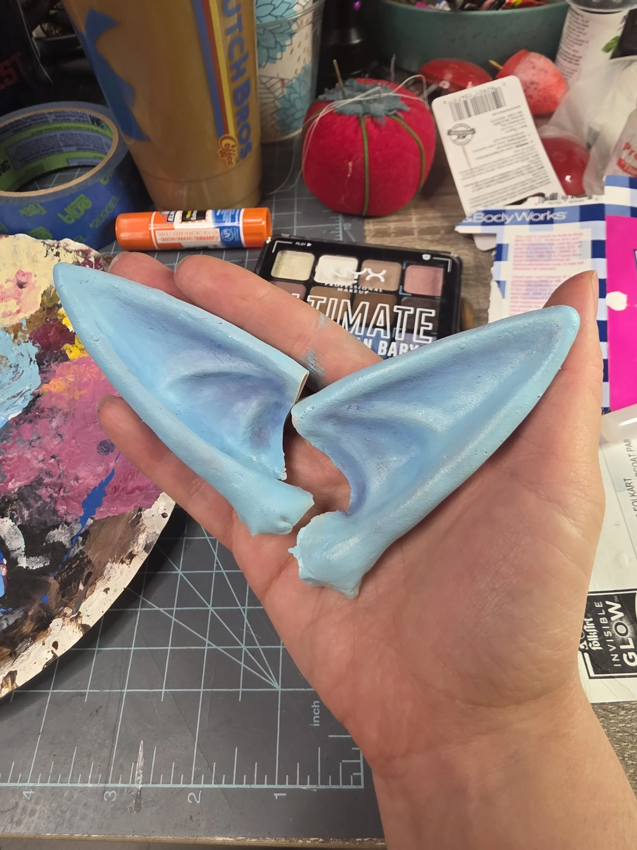 latex pointy ears, painted pale blue, with the anatomy of the ears shaded with dark blue eyeshadow