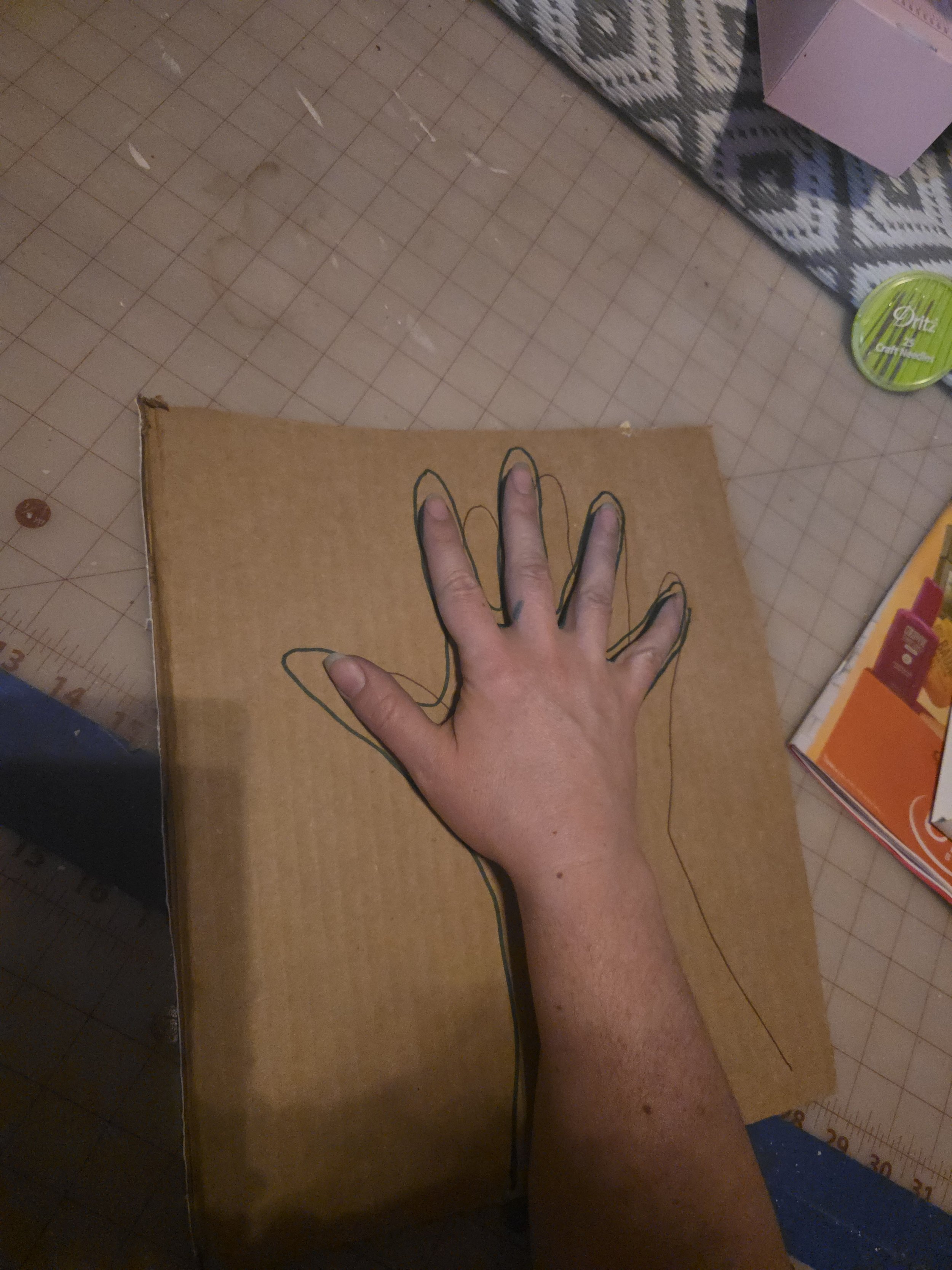 hand spread out on cardboard with a line drawn around it, like a turkey you make in school