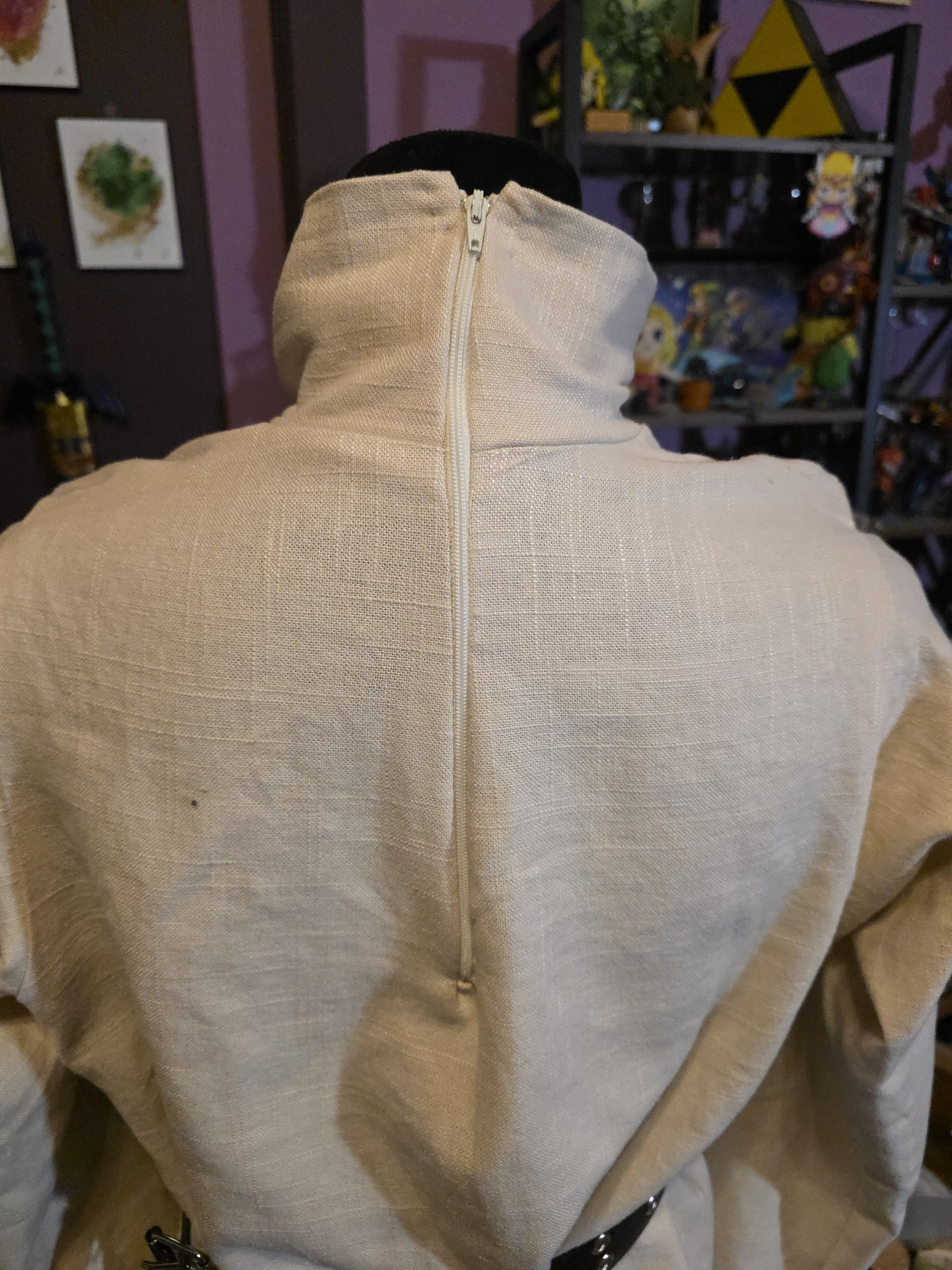 back of an off-white linen tunic, showing a thin zipper that goes from just below the shoulderblades to the top of the turtleneck