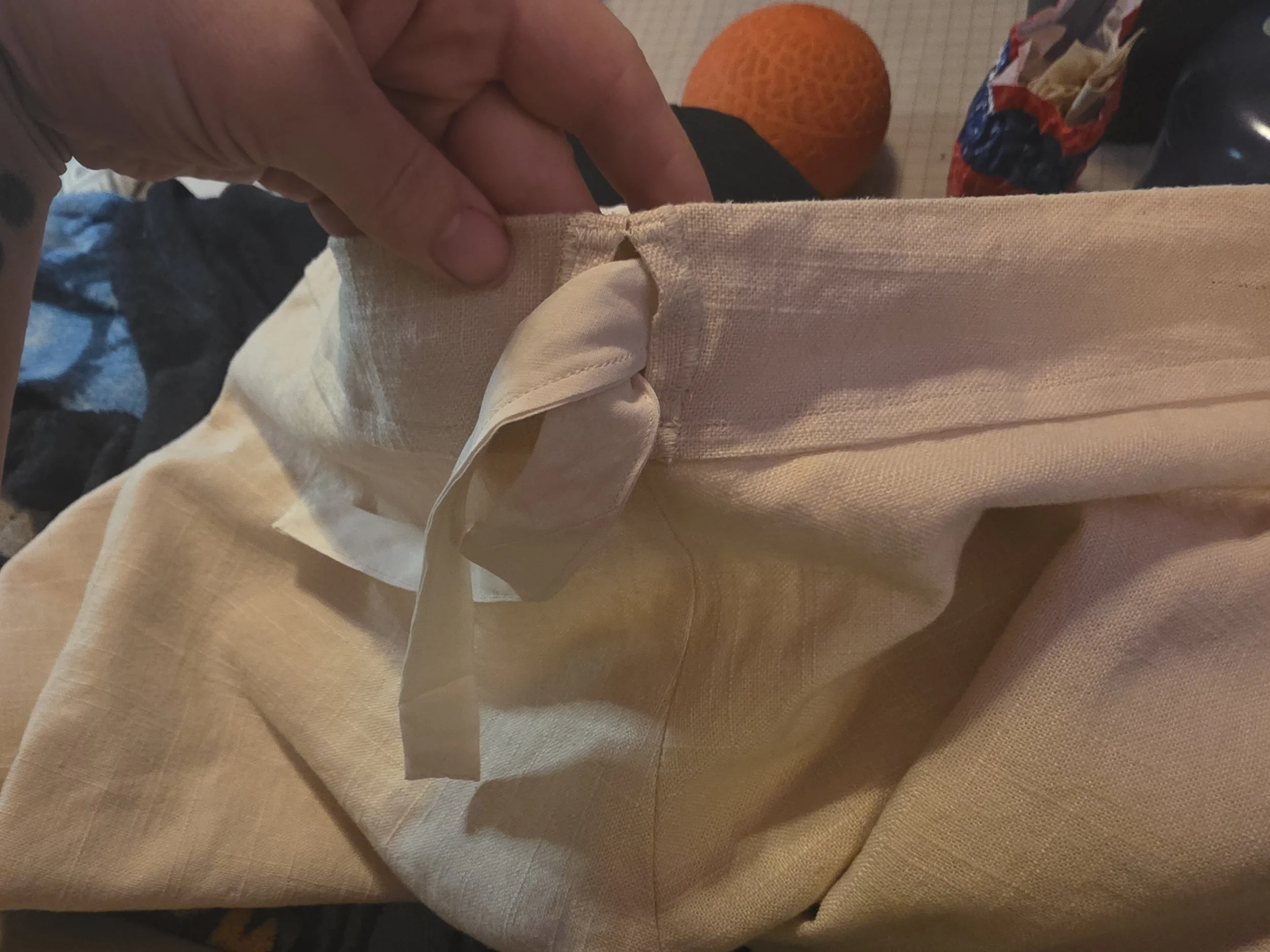 Waistband of off-white linen pants with a wide drawstring