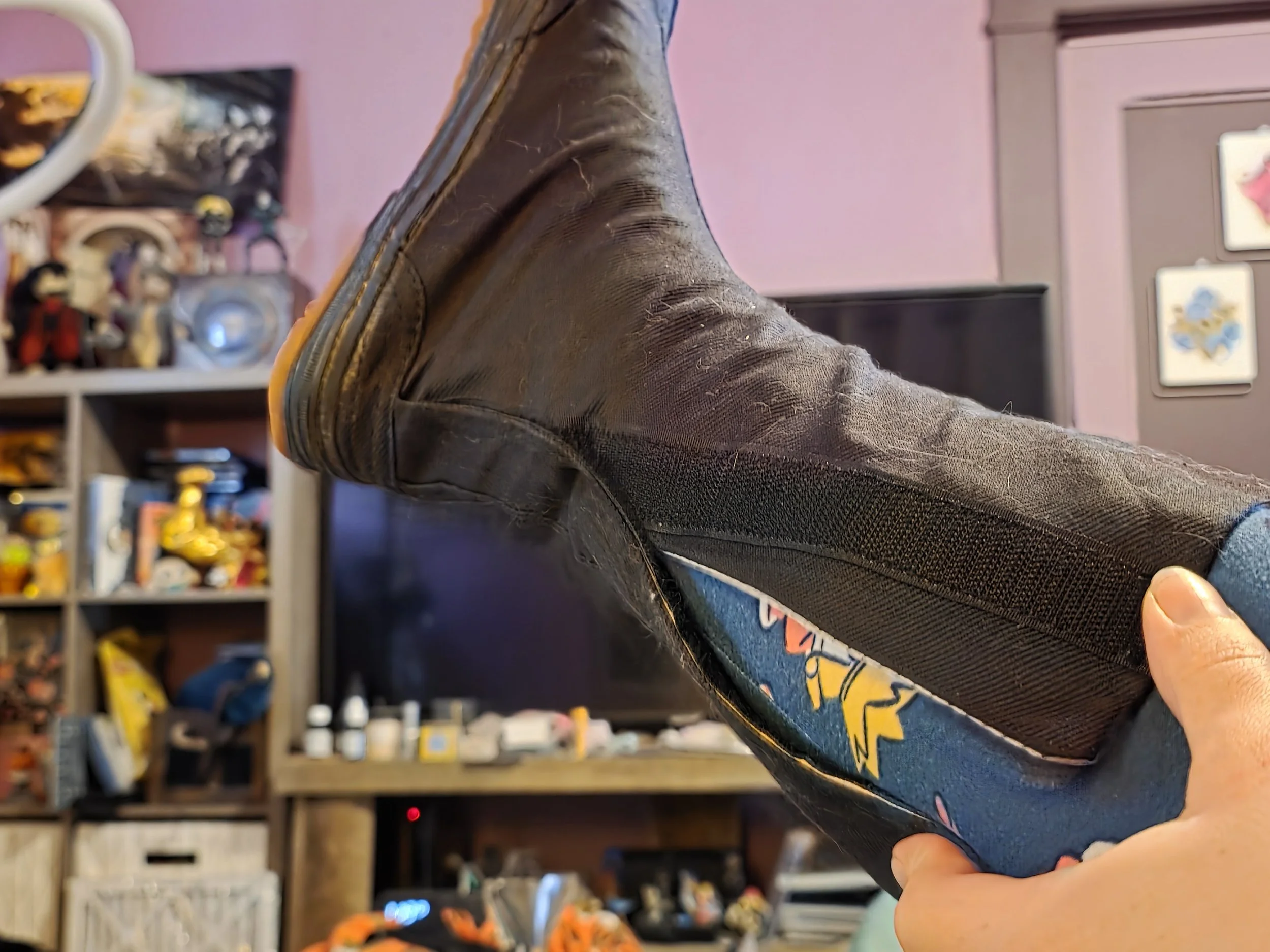 a closeup of a foot in a black canvas boot that is too small to close around the person's calf. The velcro is about 3 inches apart