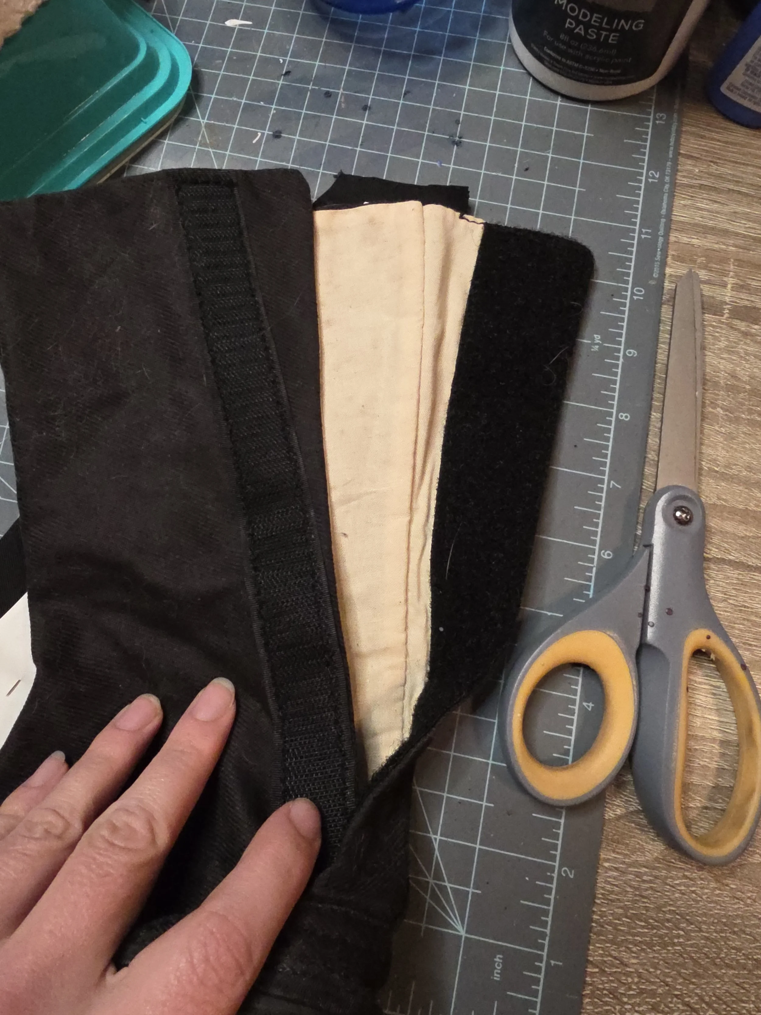 The inside of a black canvas boot, lined with unbleached fabric, showing a wide velcro strip along the opening