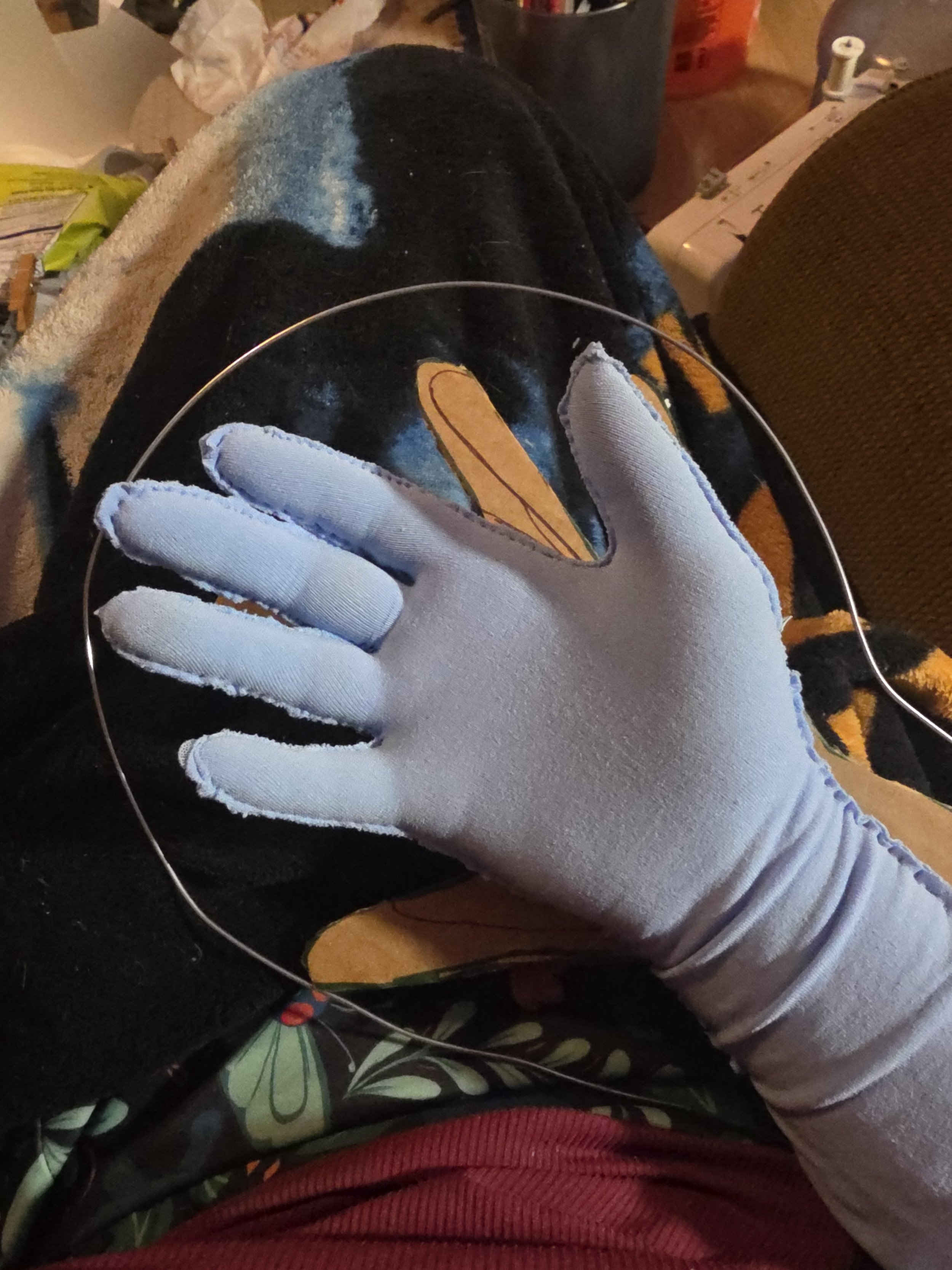 hand in a glove made of pale blue tights, with stitching visible around the sides