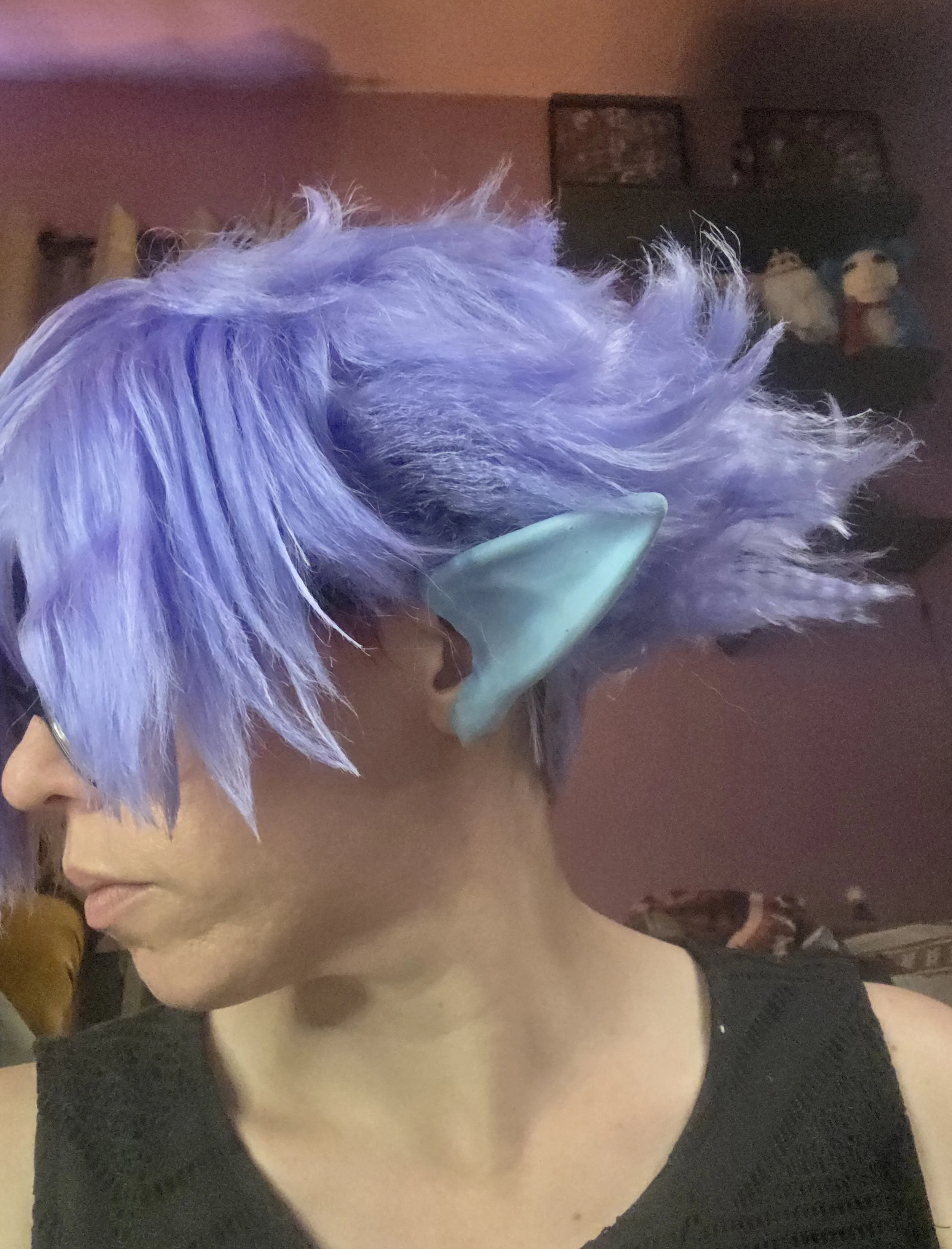 cosplayer wearing a lavender wig and pale blue pointy ears. The wig has long bangs combed over one eye