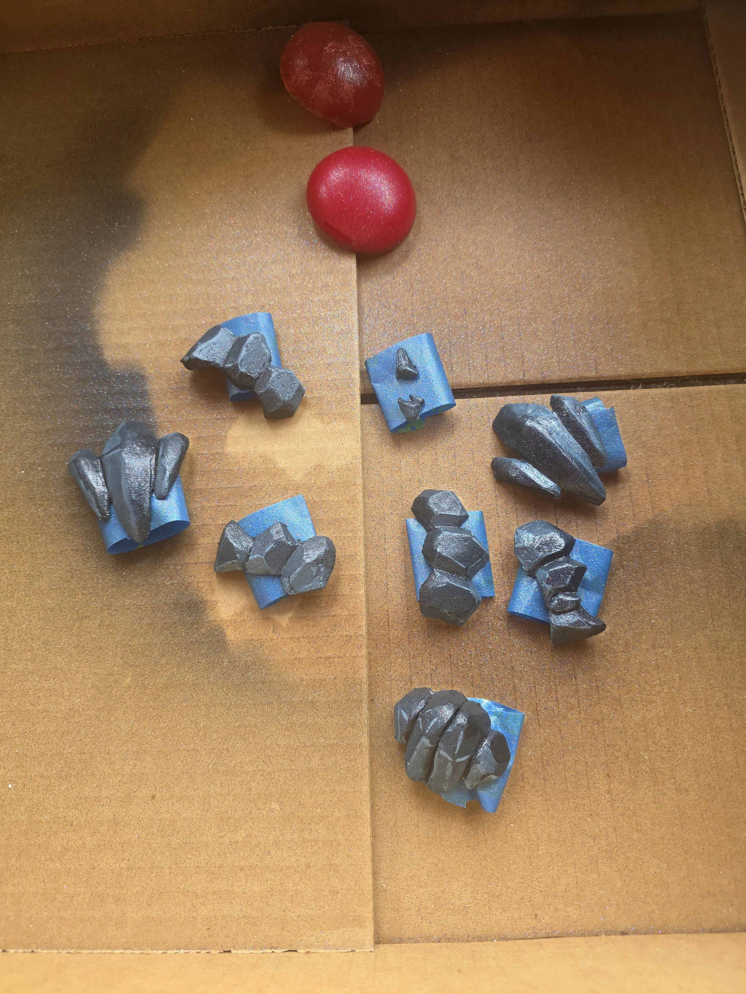 cardboard box with rock-like scales made of worbla. smooth, angular planes on each rock are painted different shades of blueish gray to create shading