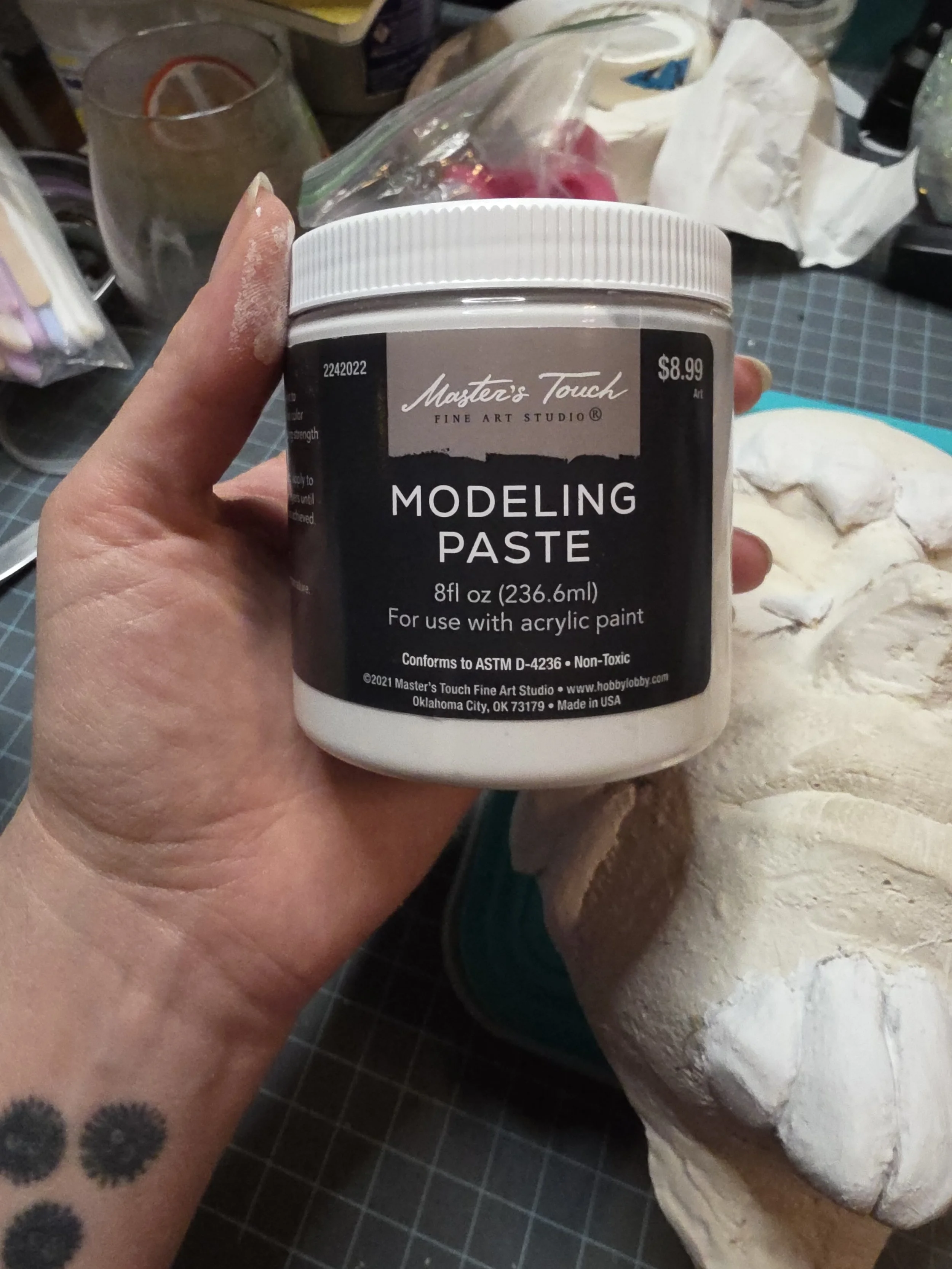 hand holding a jar of white modeling paste