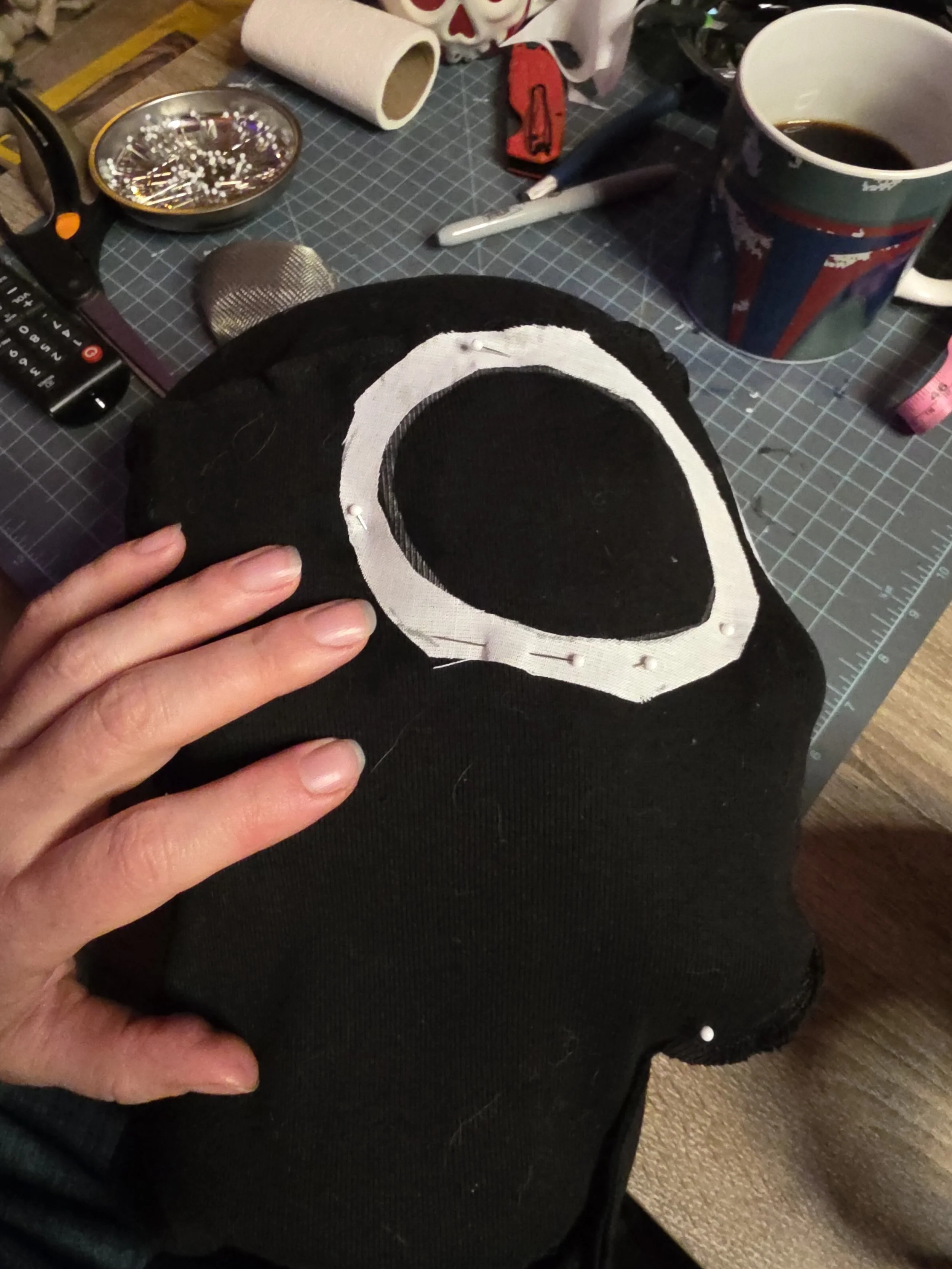 Ring of iron-on interfacing fabric pined around the eye hole area of an inside-out ninja hood. The eye hole is not cut out yet
