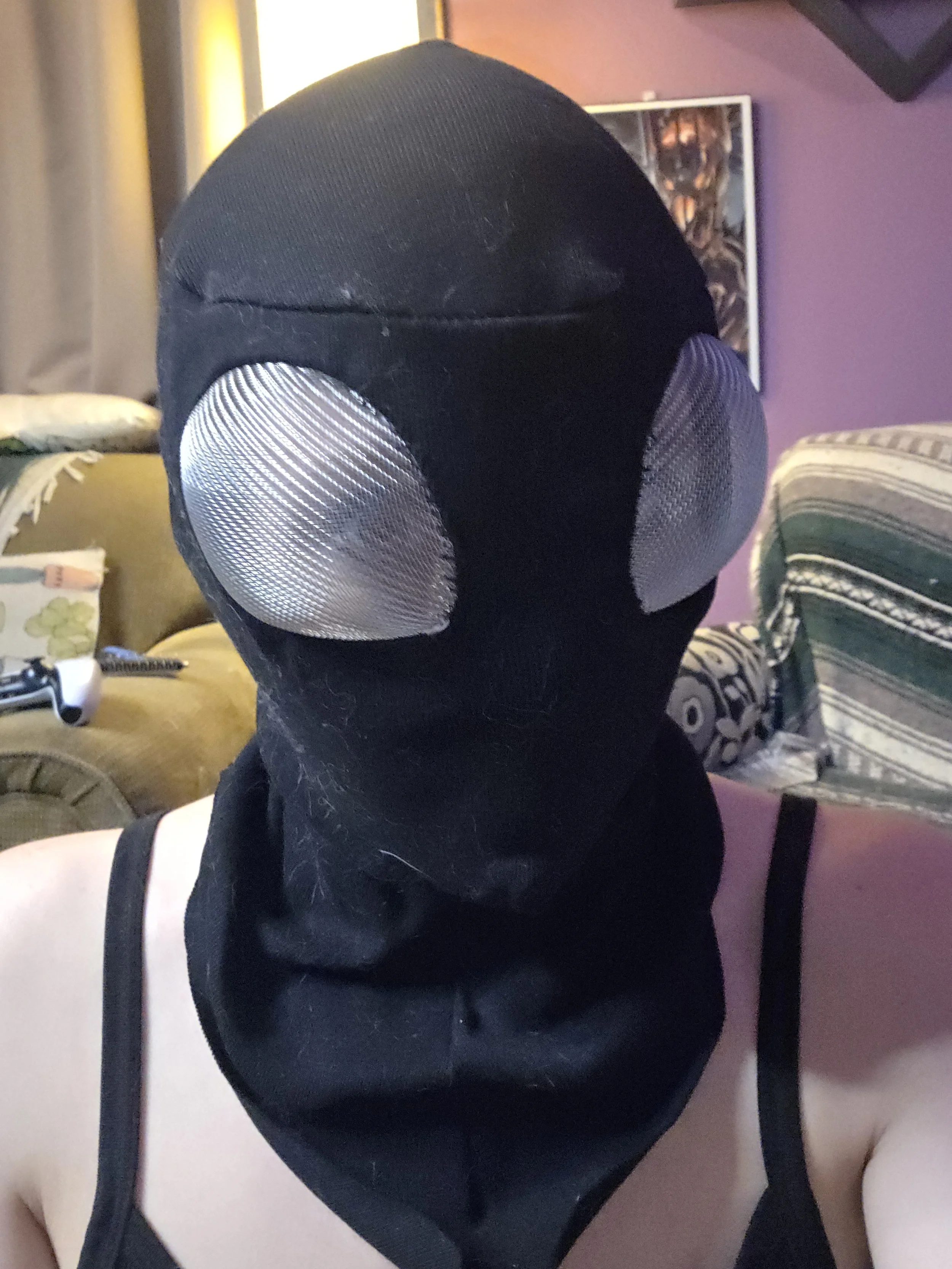 Person wearing a black ninja hood with bug-like metal mesh eye covers