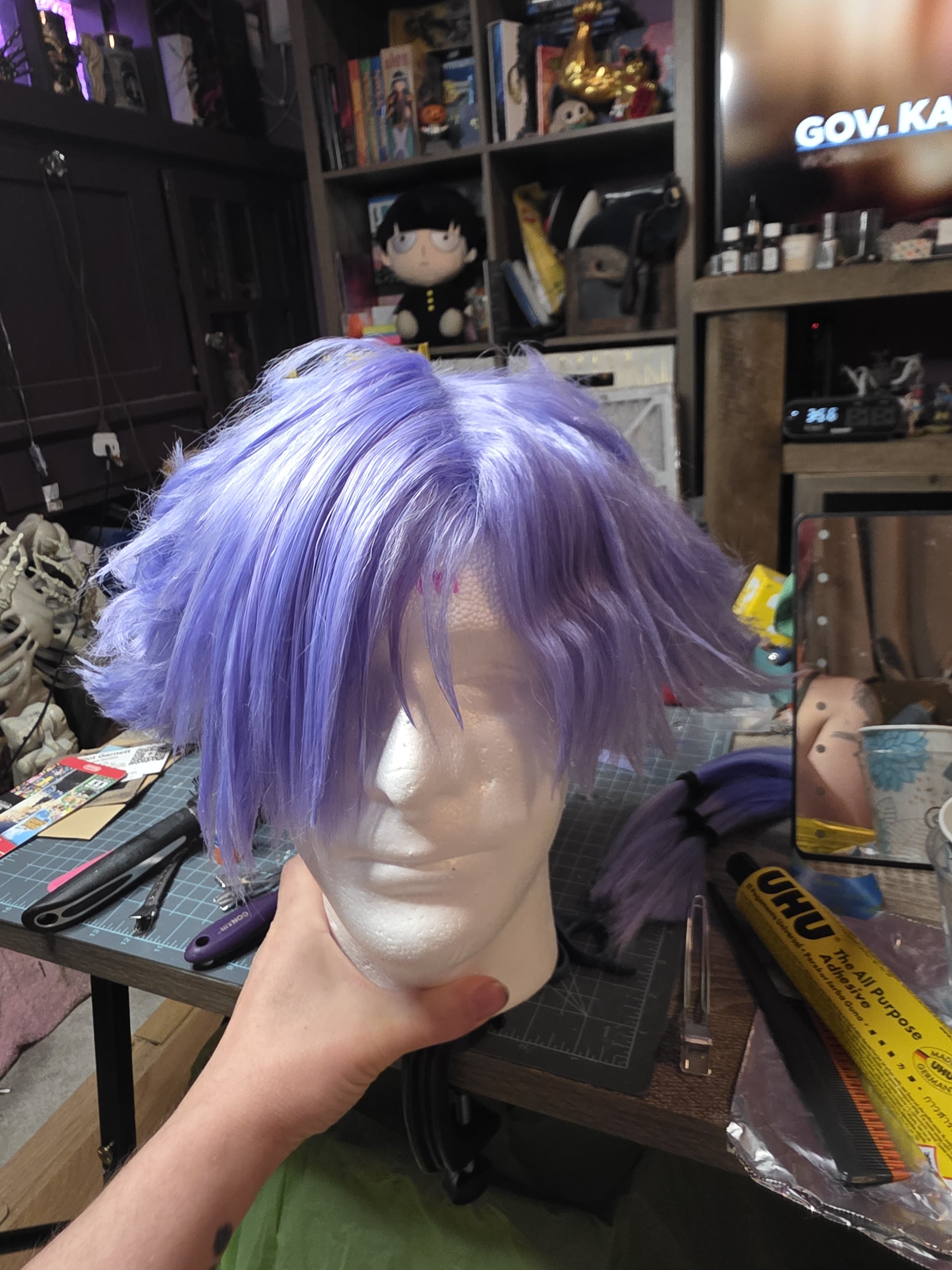 short lavender wig with long bangs combed over one eye. the sides are spiked outwards