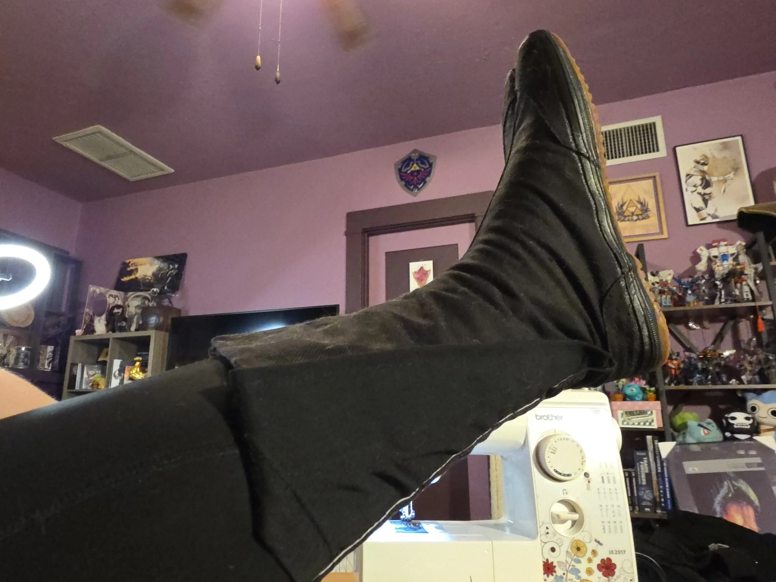 A foot in a black canvas tabi boot, with a triangle of black fabric sewn into the inside opening flap to make the calf wider. The boot is velcroed closed around the leg