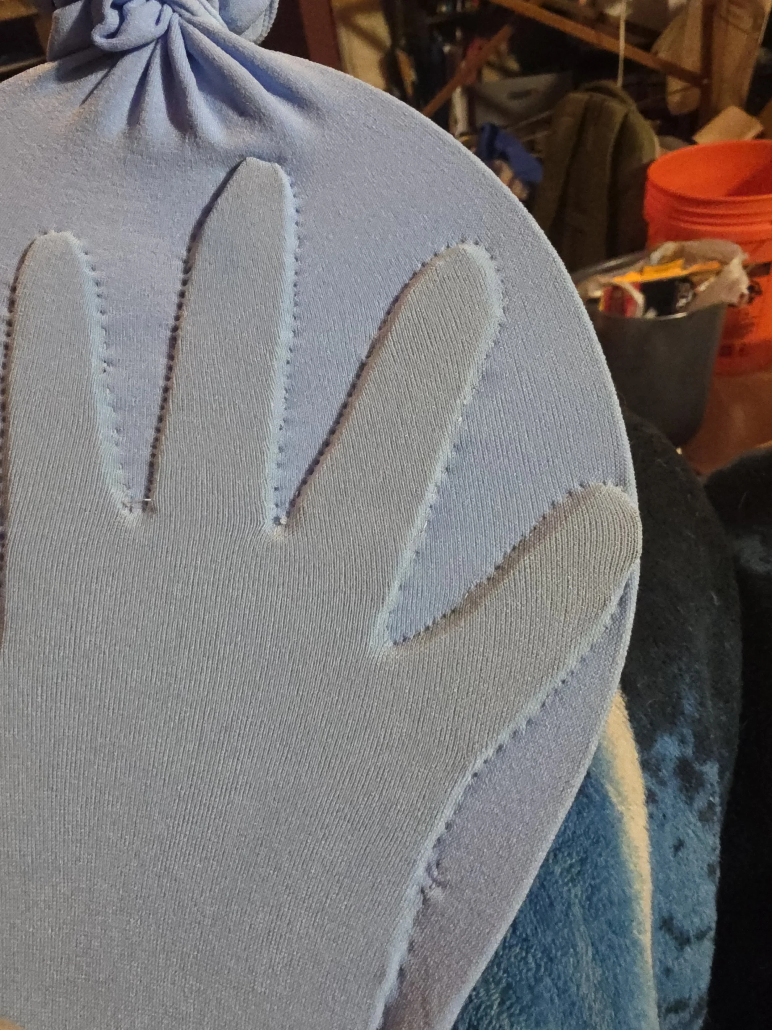 blue tights stretched over a wire hoop surrounding a cardboard hand cutout. The tights are stitched around the cardboard to make a glove