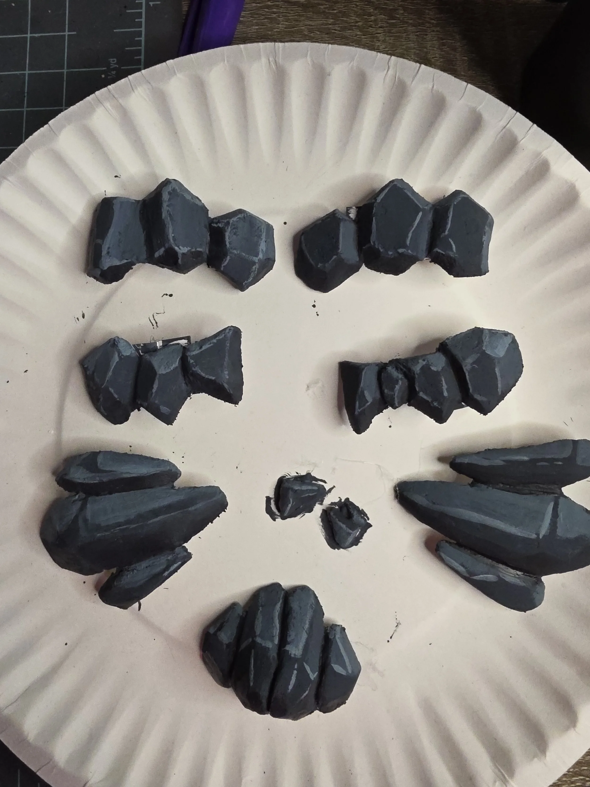 paper plate with rock-like scales made of worbla. smooth, angular planes on each rock are painted different shades of blueish gray to create shading