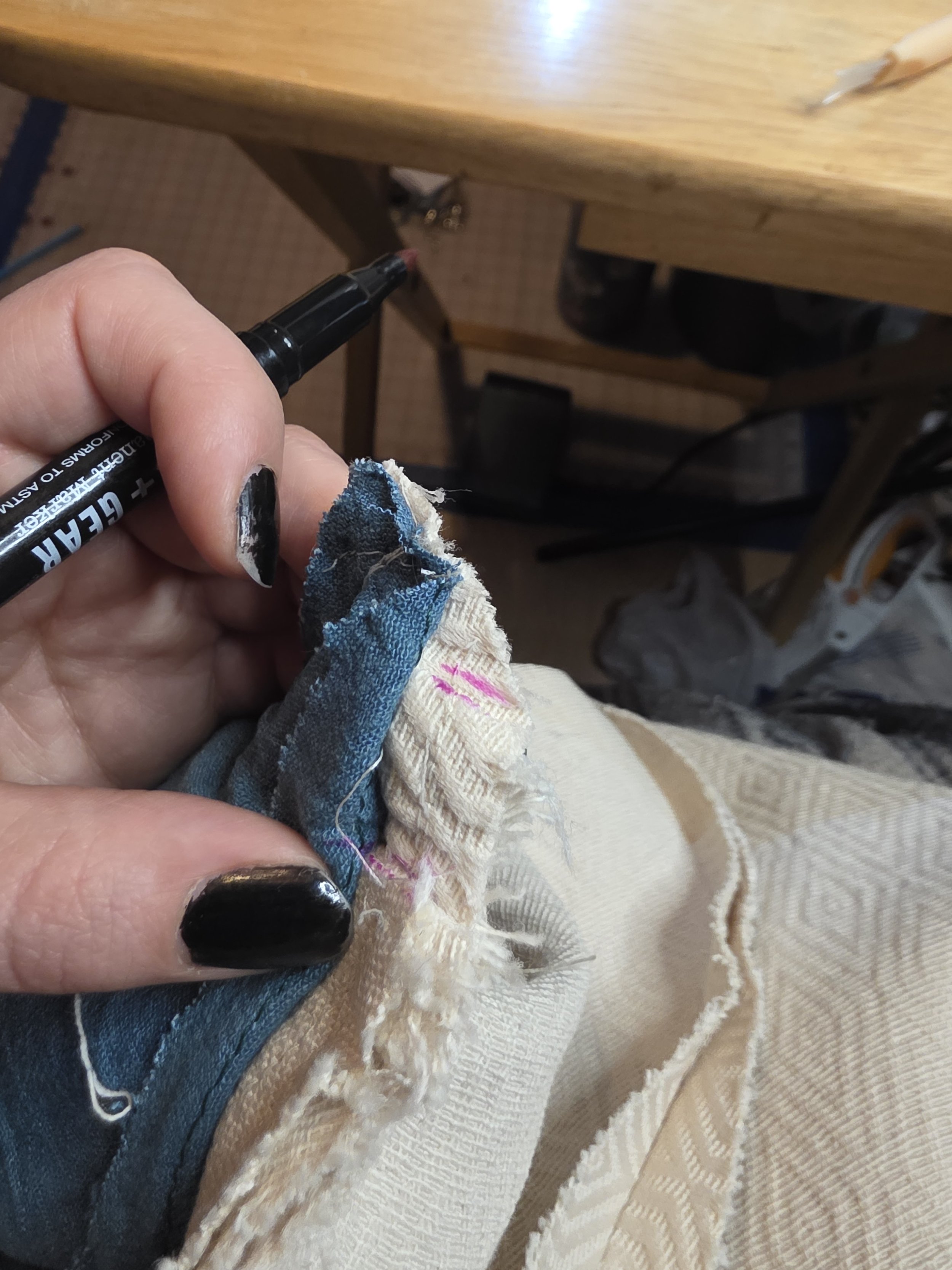 the inside layers of a linen cape being un-stitched, showing the off-white cape, capelet, and hood, and the dark green lining