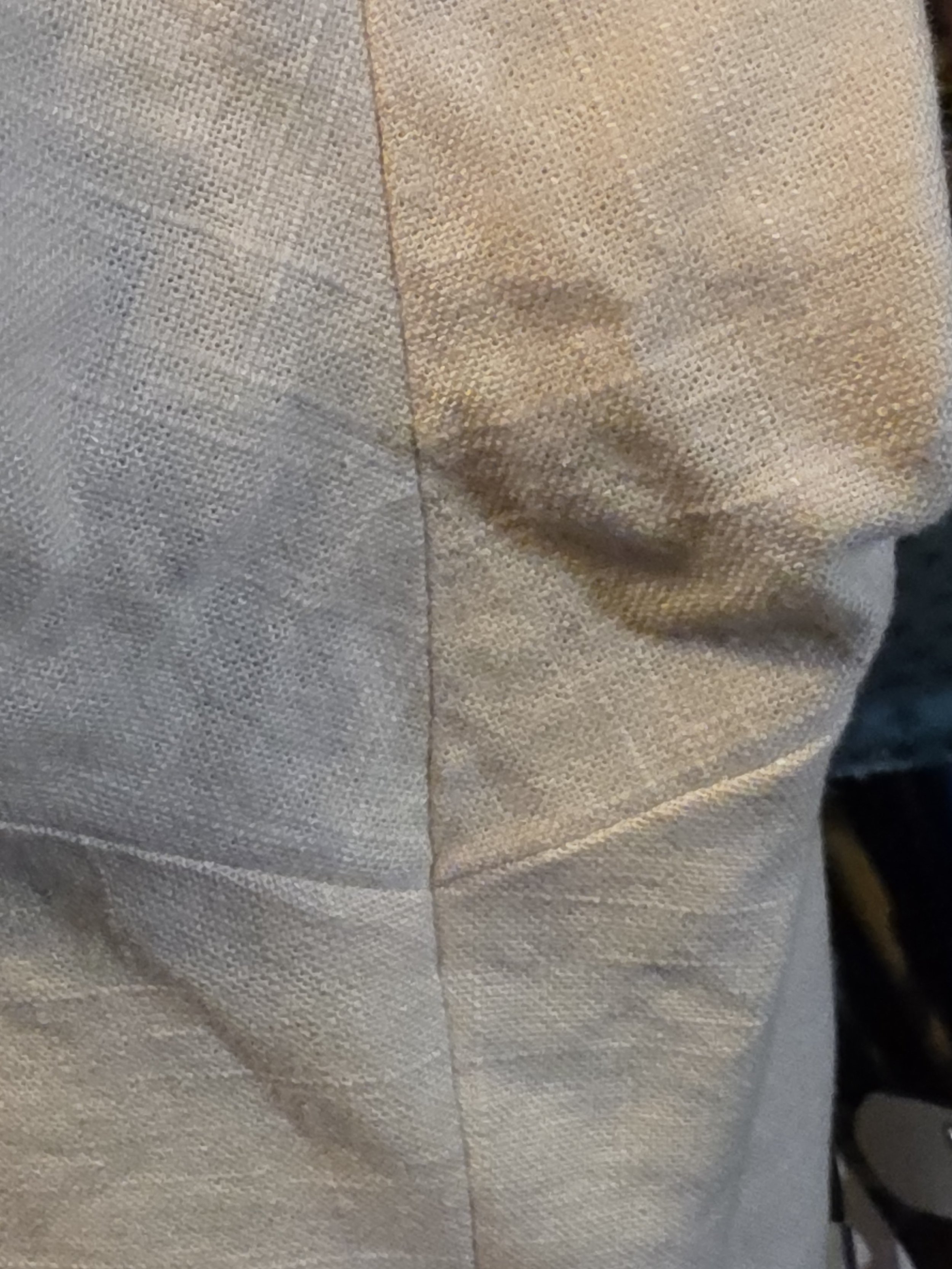 closeup of blessed seams in the underarm of an offwhite linen tunic. 2 seams cross over and are precisely matched at the point where they cross