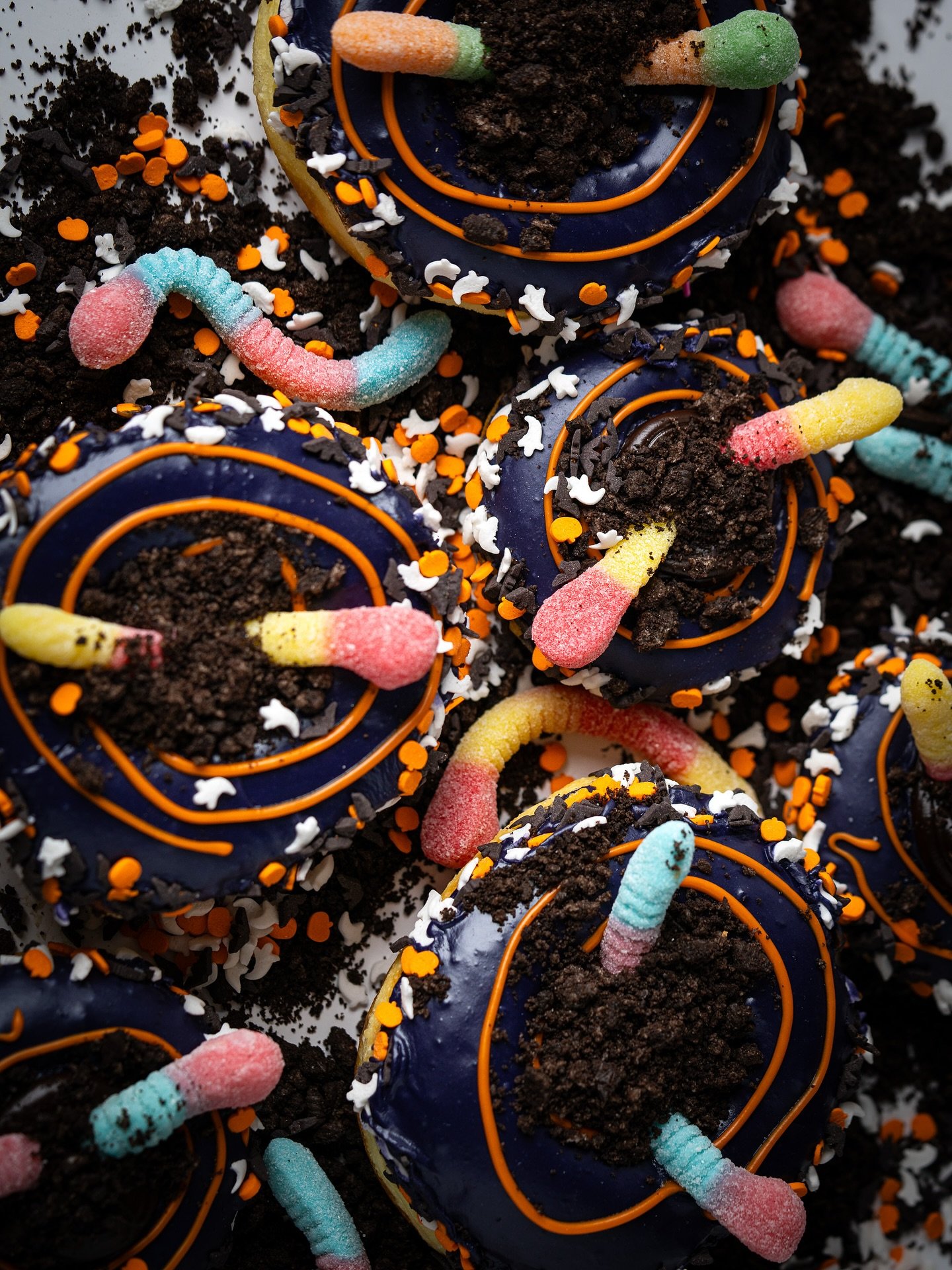 Creepy, crawly, and crazy delicious! 🪱🎃 Our Halloween Dirt &amp; Worms donut is stuffed with chocolate fudge, dipped in blueberry-orange glaze, and topped with Oreo crumble, sour worms, and spooky sprinkles. Available now until Halloween 👻 🍩