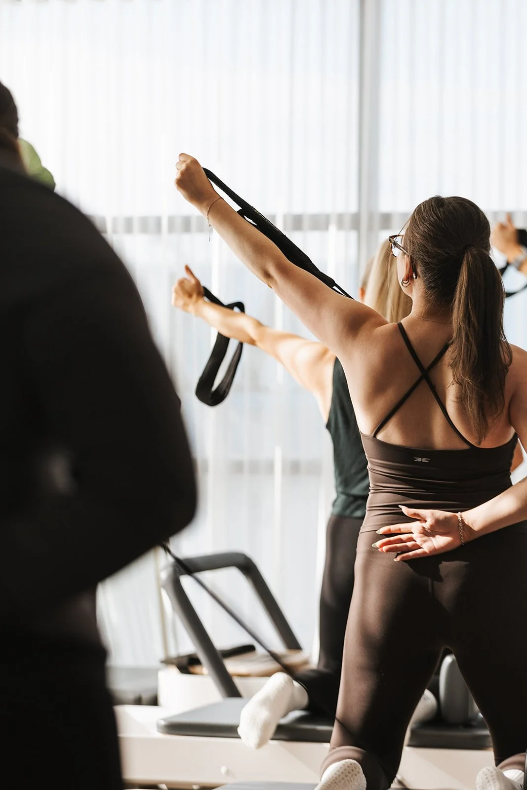 Member performing an upper body exercise on a reformer during a Reformer Pilates session at Vybe Movement in Cranbourne.