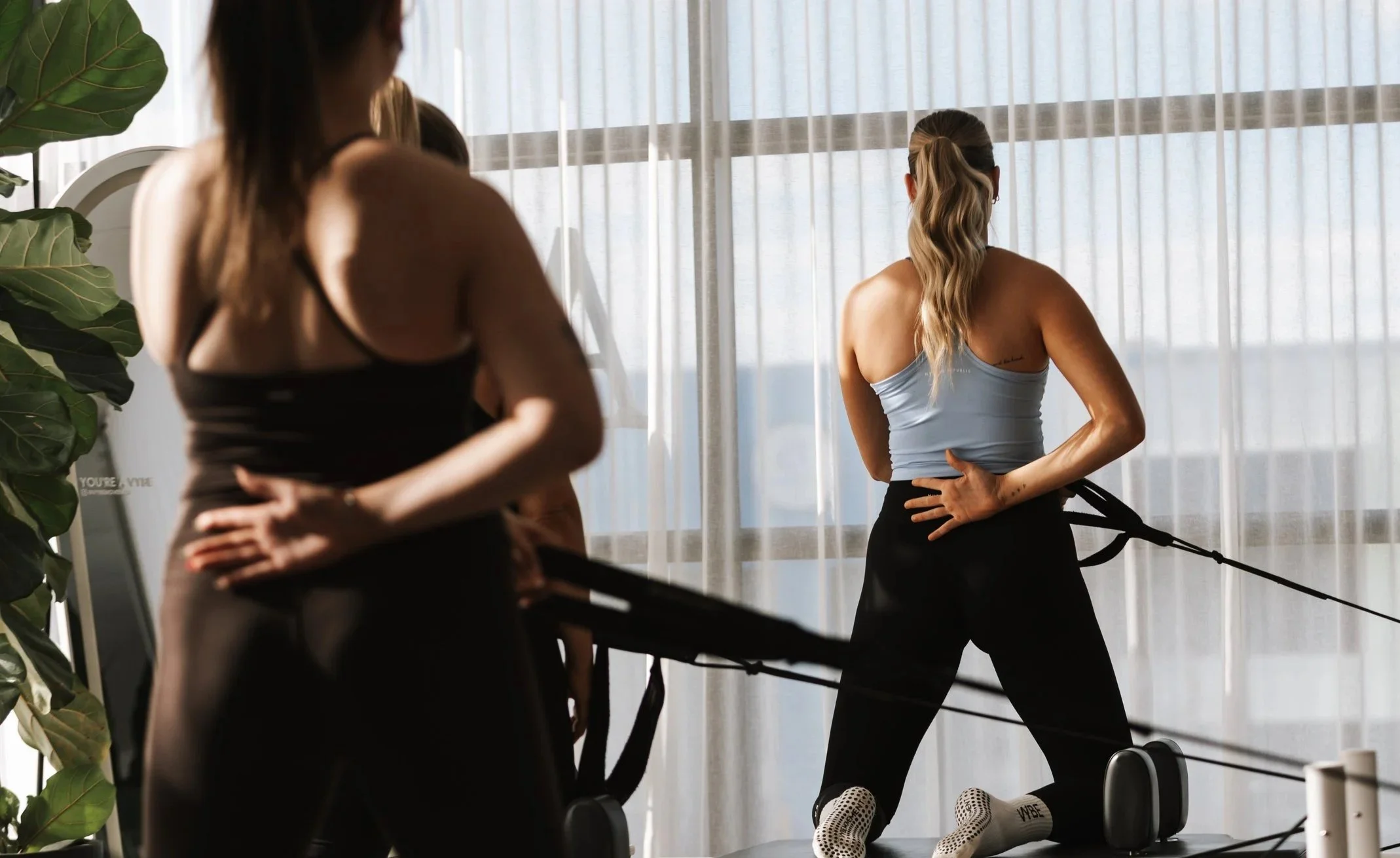 Members performing an upper body exercise on a reformer during a Reformer Pilates session at Vybe Movement in Cranbourne.