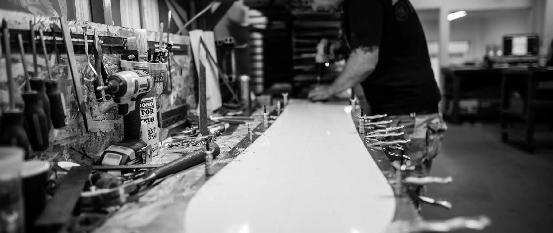 A workbench with various tools and a person assembling or working on a project in a workshop.